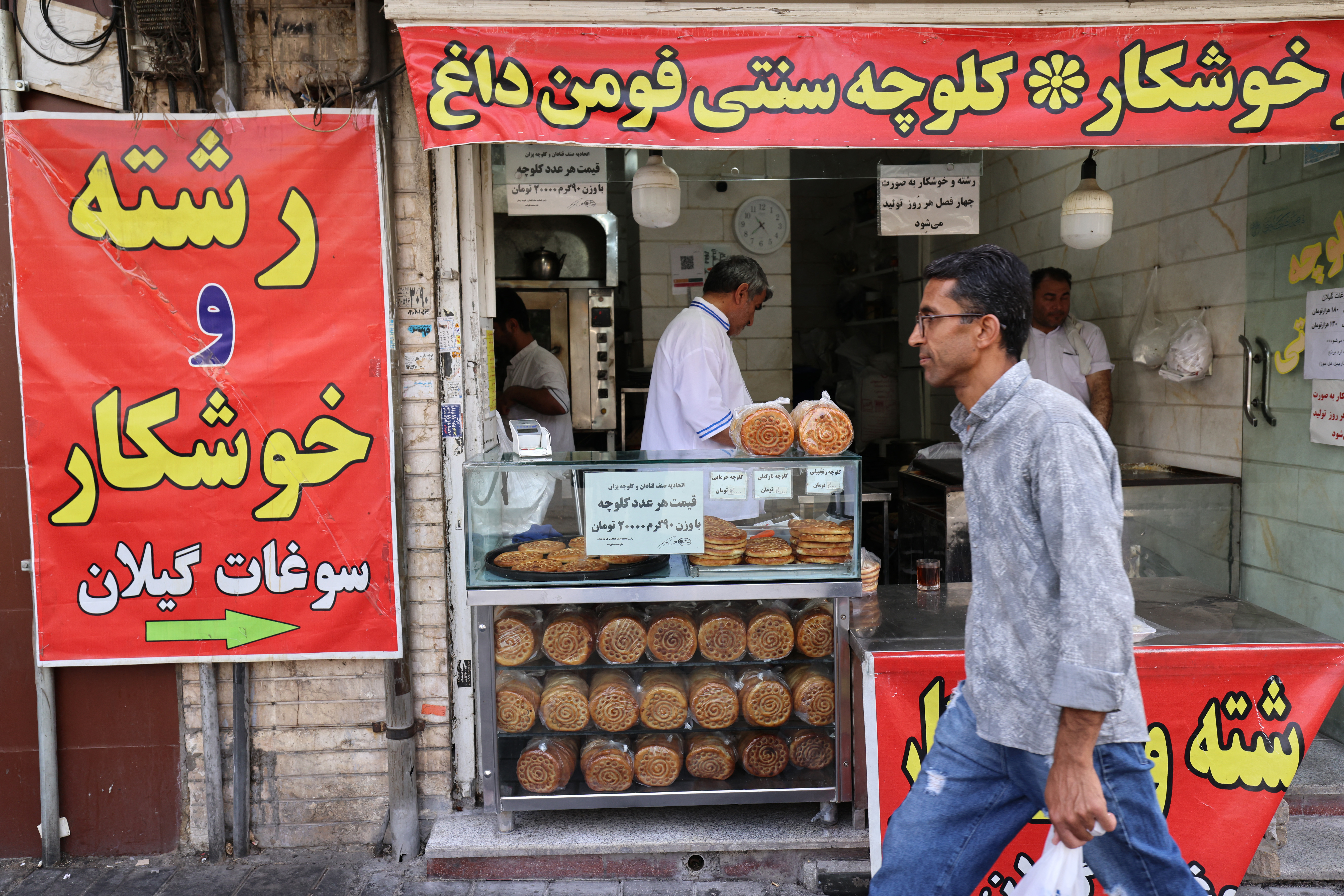 An Iranian man walks past a bakery in Tehran's Enghelab (Revolution) Square on June 24, 2025, following US President Donald Trump's announcement of a phased 24-hour ceasefire process which began early in the morning. (Photo by ATTA KENARE / AFP)
