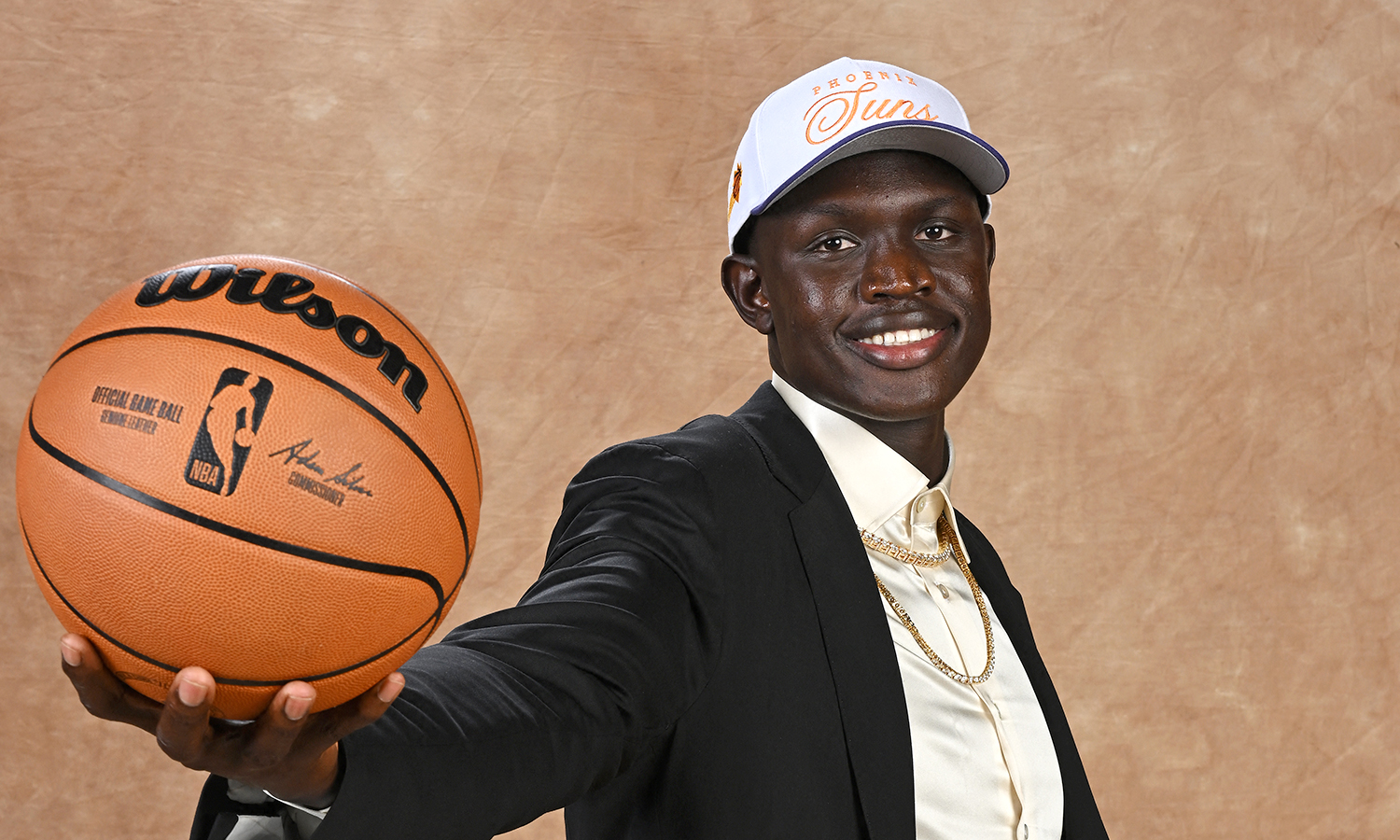 Khaman Maluach poses for a photo as he holds out a basketball.