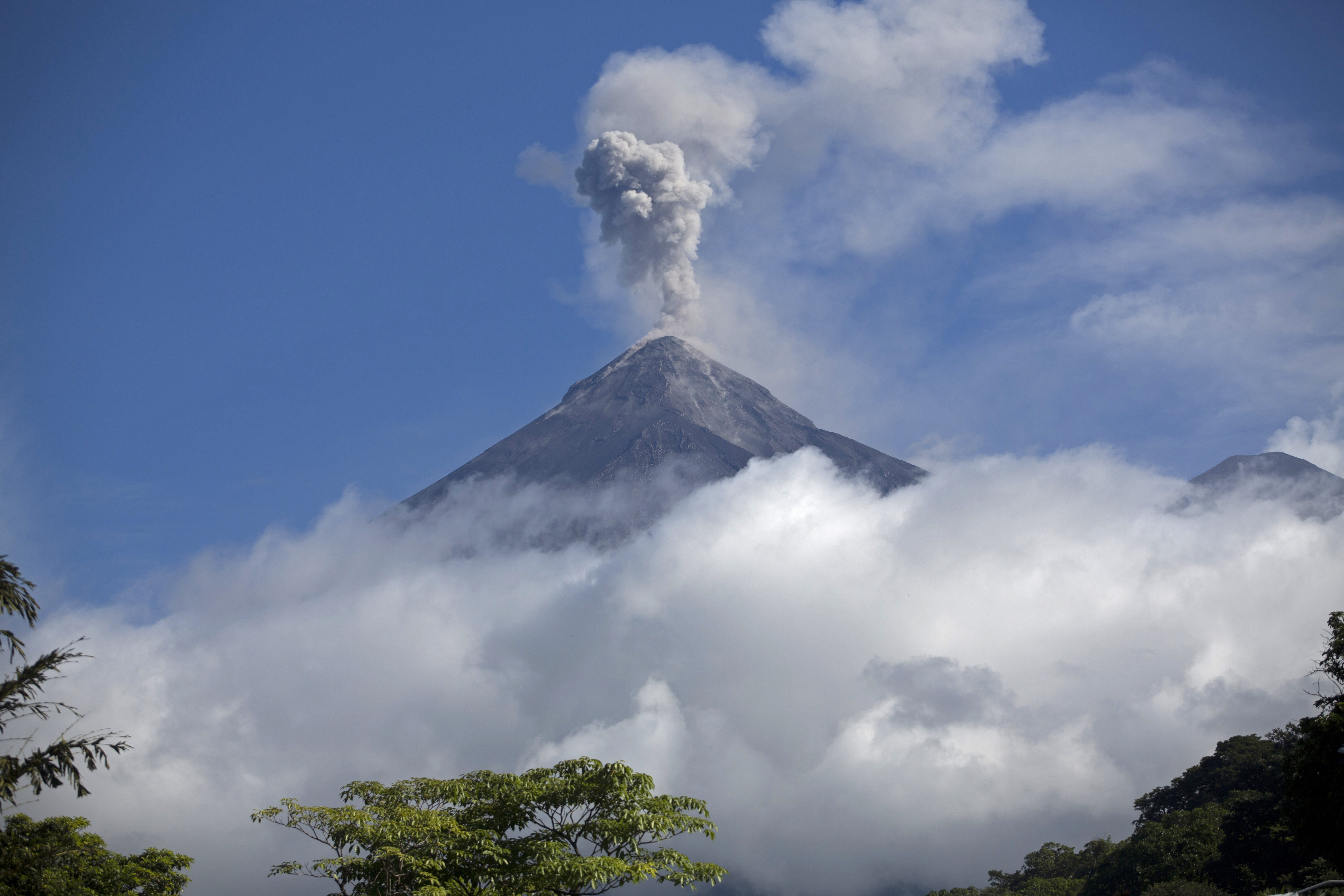 A volcano blows out a thick cloud of ash.