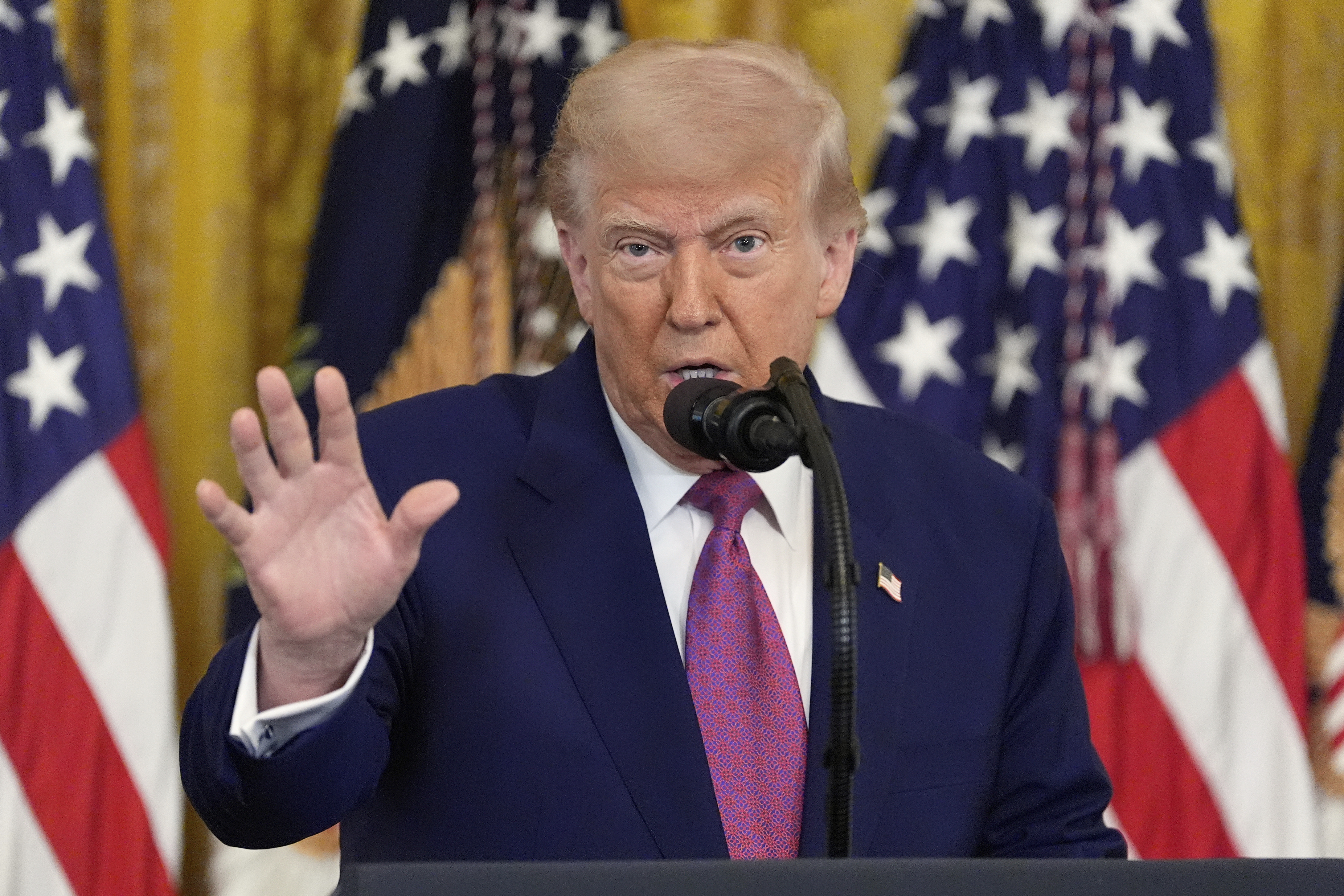 Donald Trump speaks in the White House in front of US flags.