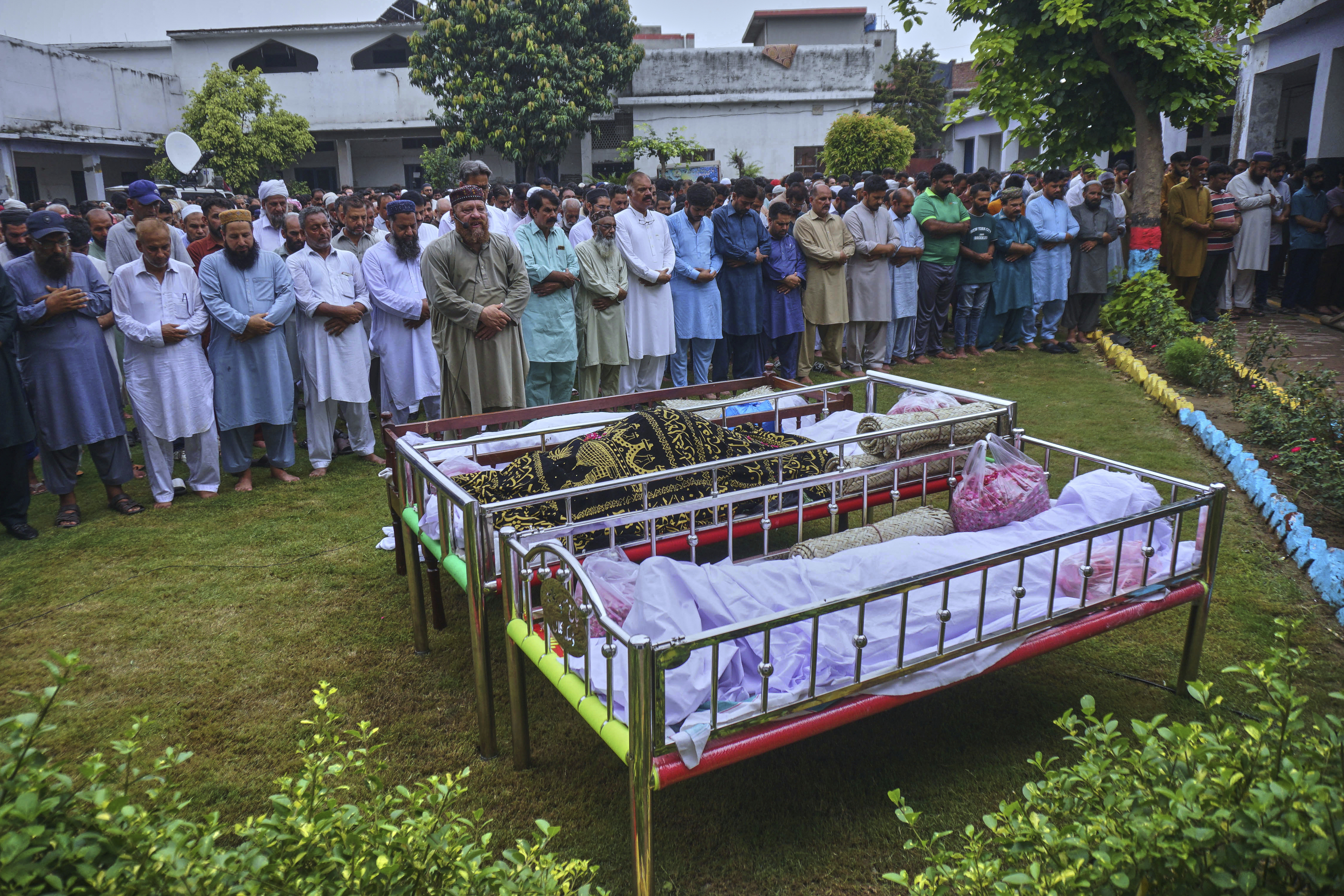 People attend funeral prayers of the victims who swept away by the floods in the Swat River, in Daska, Pakistan, Saturday, June 28, 2024. (AP Photo/S.A. Rizvi)