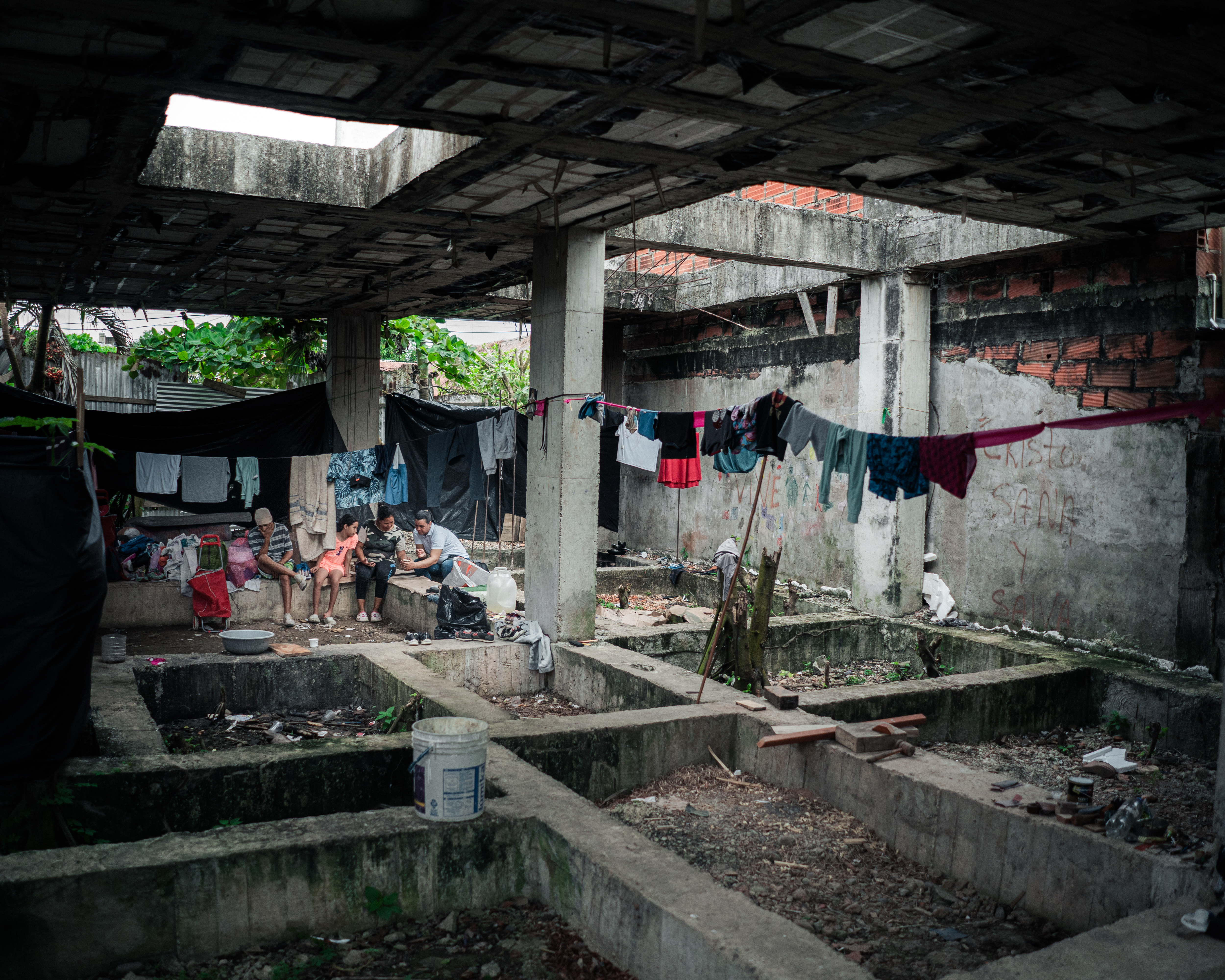 Marisela, Yeral and their children have made a half-constructed building a temporary home. Here, they are pictured talking with an aid worker who is visiting the family.