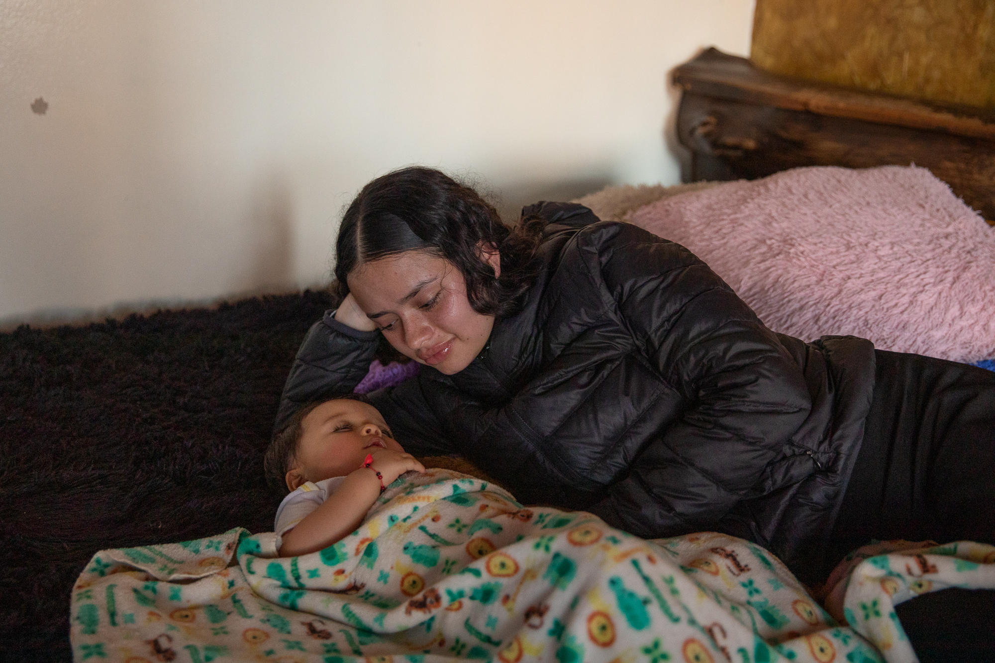 Jennyfer Ramirez lies on a bed while a baby cousin sleeps.