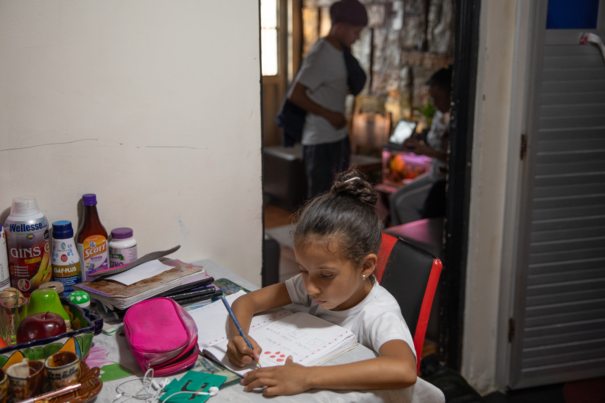 Luna Castro, a little girl, writes at a table at her grandmother's home.