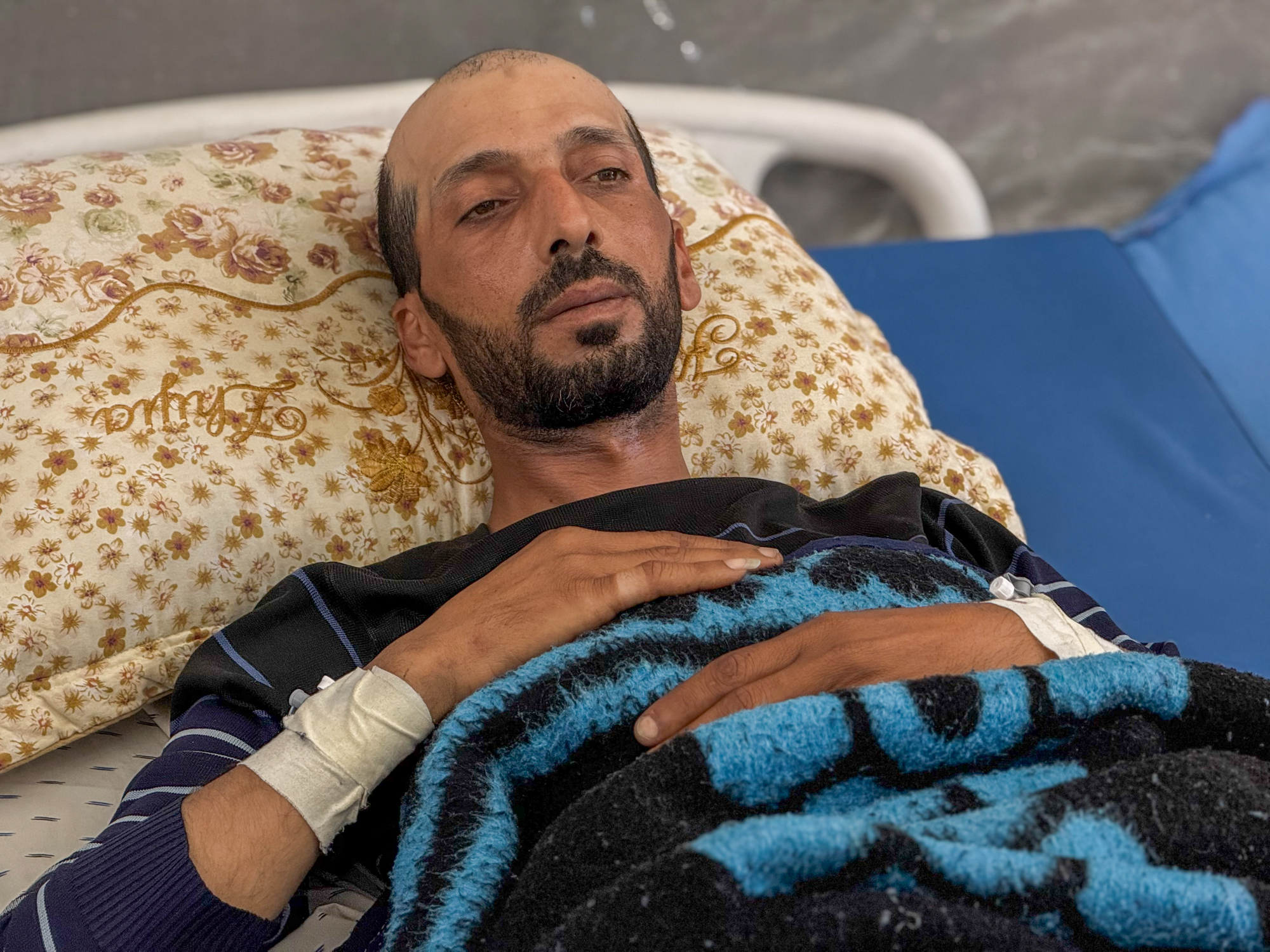 Khaled al-Lahham lies fretfully in a hospital bed. He is thin, balding, and looks like he's in pain