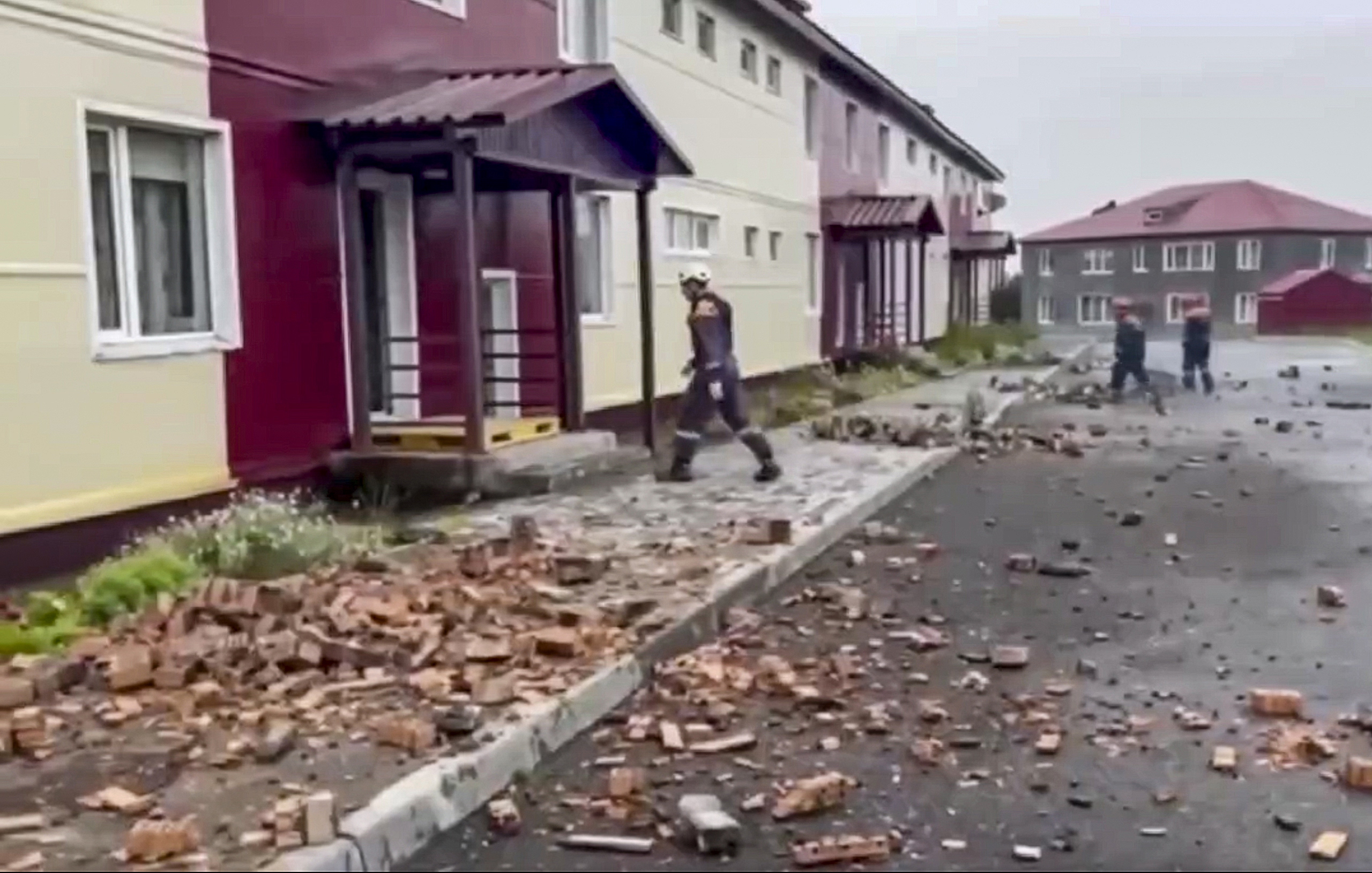 A still image taken from a handout video provided by the Russian Emergencies Ministry shows rescuers walking among debris in front of a damaged building following an earthquake, in Petropavlovsk-Kamchatsky, Kamchatka