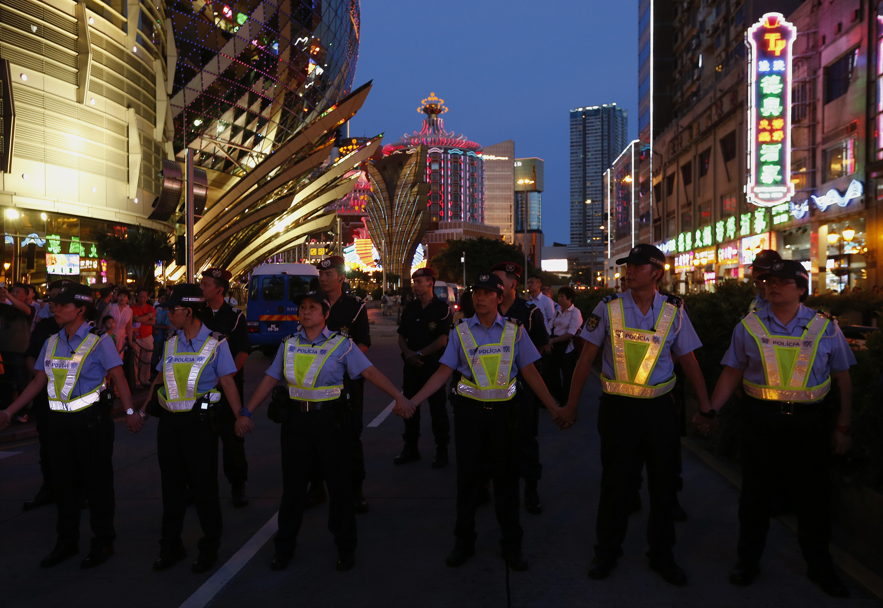 Police form a cordon during a protest march by workers from Macau's six major casinos, led by union "Forefront of Macau Gaming", in Macau August 25, 2014. More than one thousand protesters took part in the march on Monday, demanding higher wages and for the government to reconsider a policy that would import more foreign workers to the industry. REUTERS/Bobby Yip (CHINA - Tags: CIVIL UNREST POLITICS BUSINESS EMPLOYMENT)
