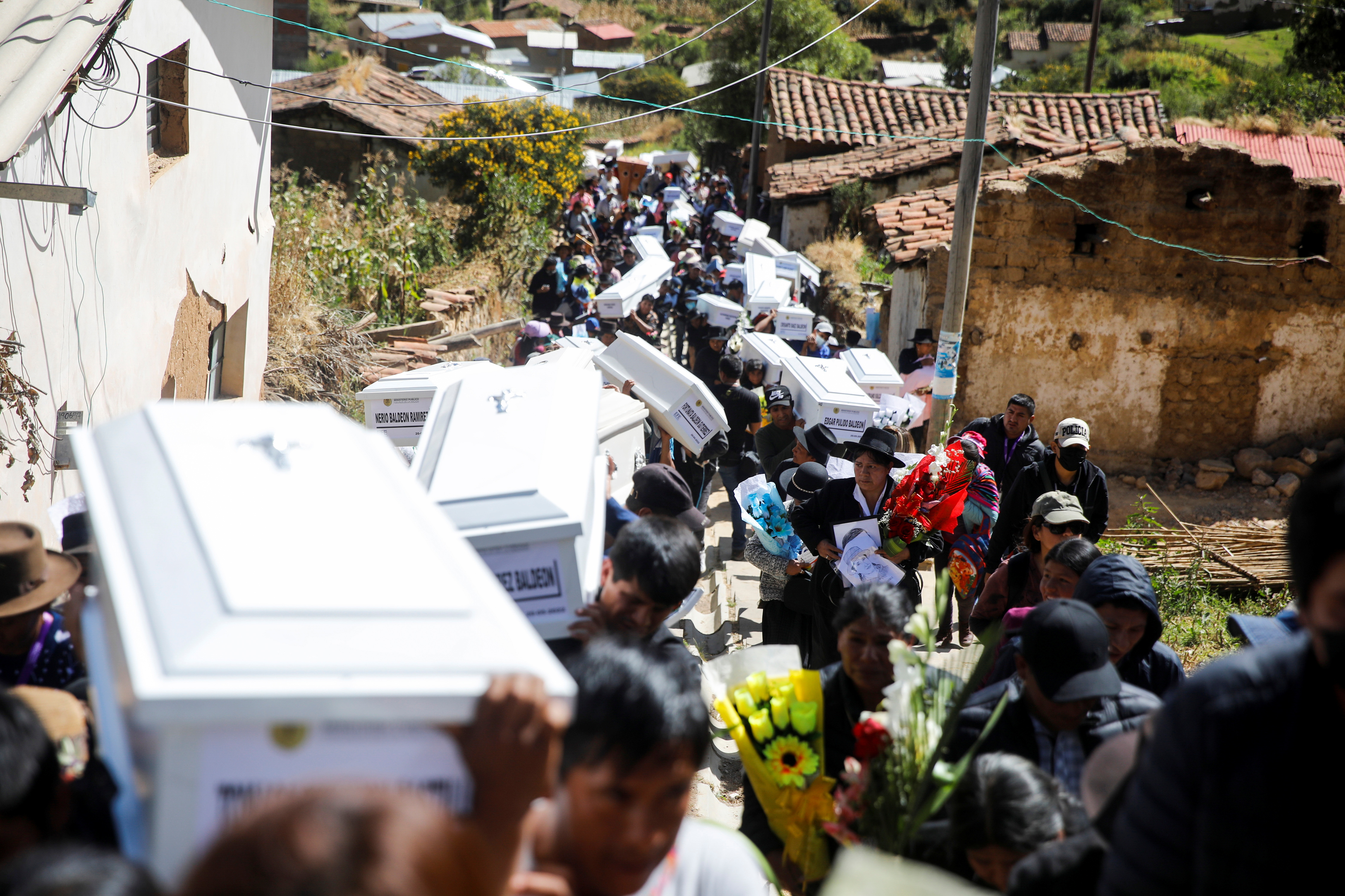 A line of mourners carries white coffins in Accomarca
