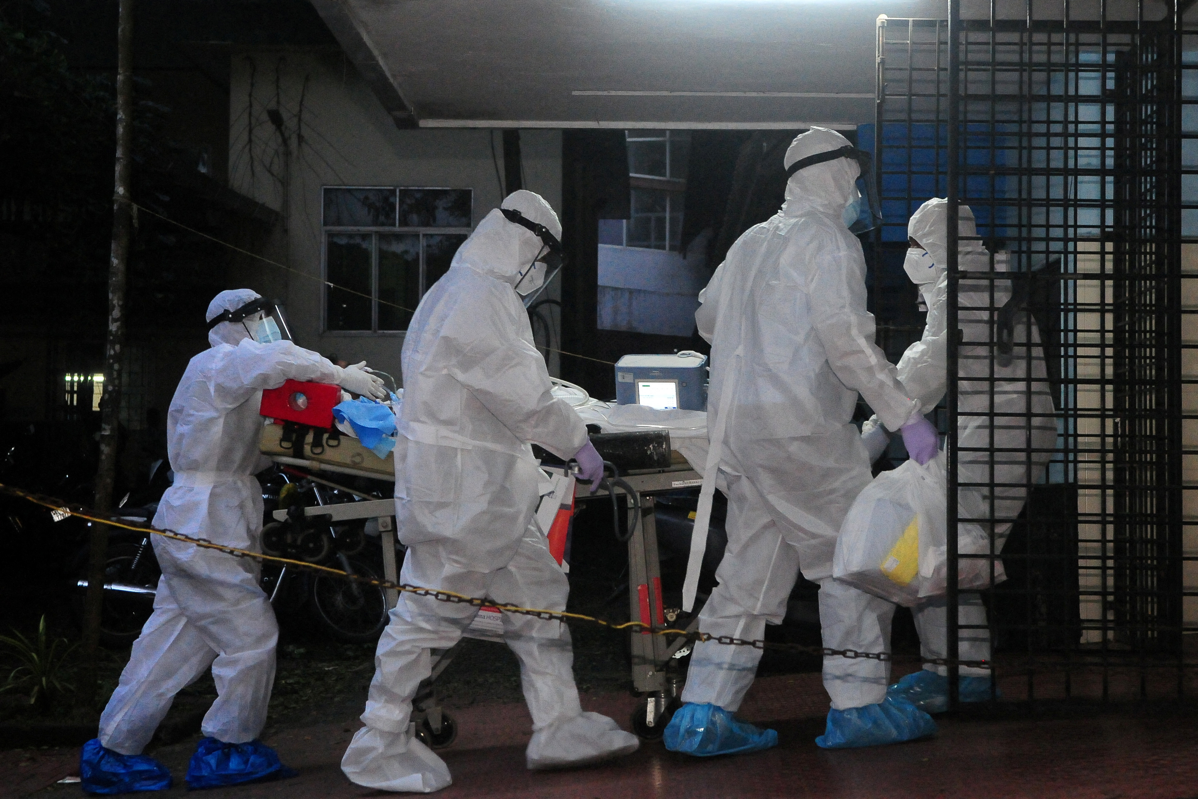 A patient is moved to an isolation ward in a hospital, by medics wearing protective gear.