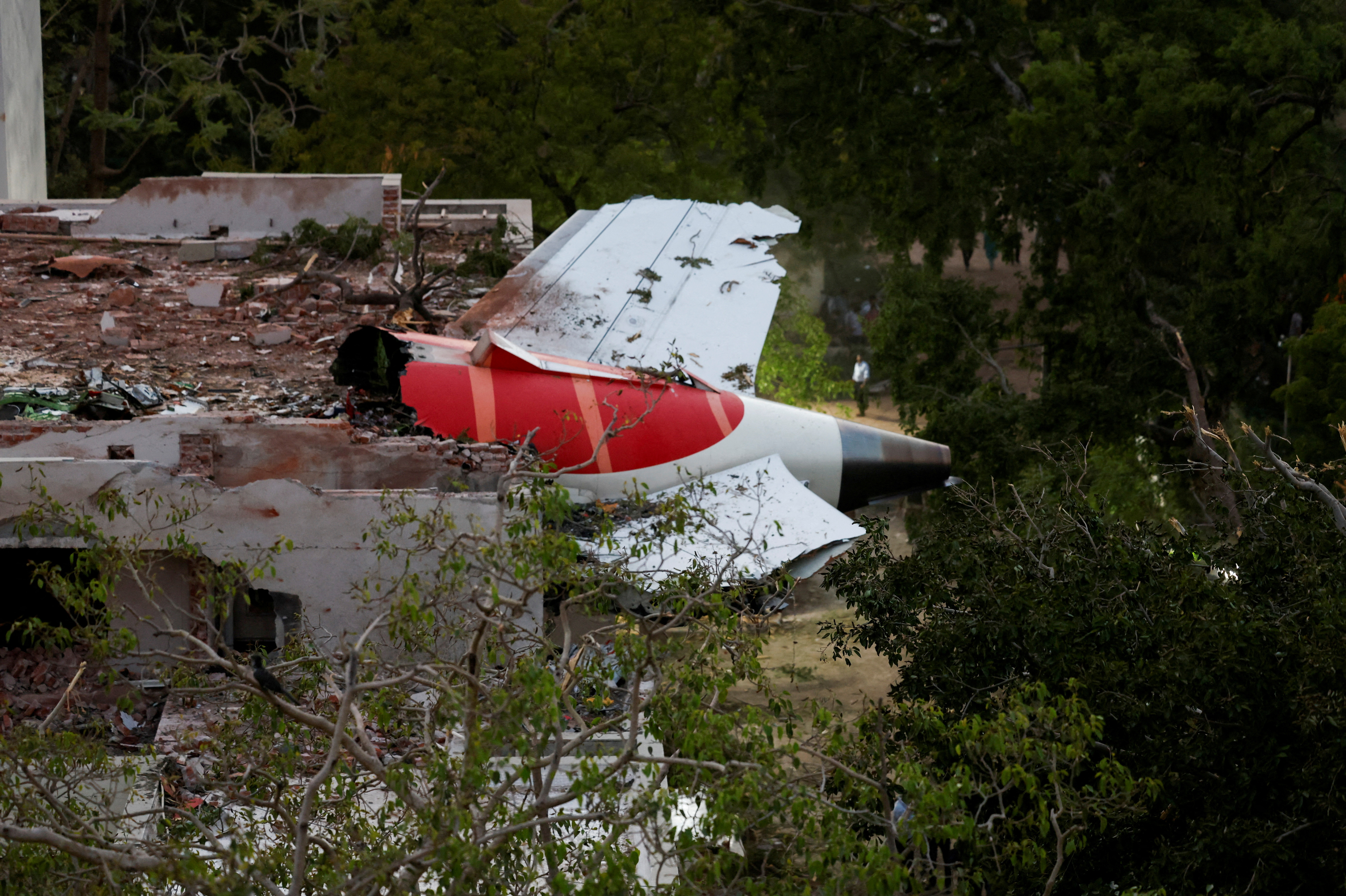 Tail of an Air India Boeing 787 Dreamliner plane that crashed is seen stuck on a building.