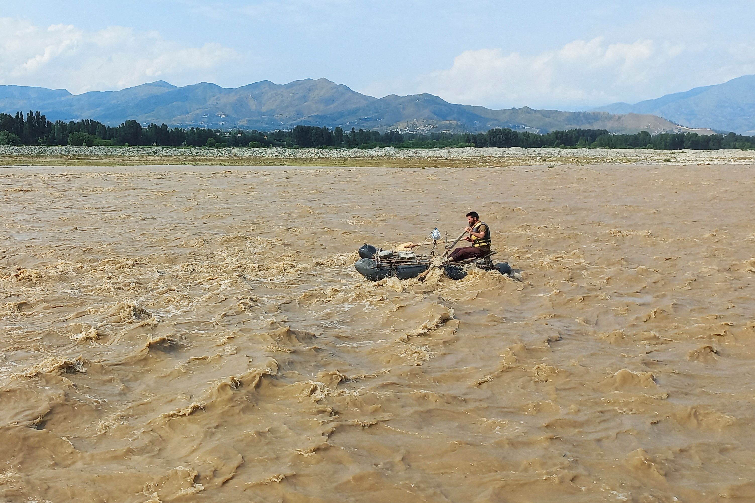 A rescue worker rows a raft while searching for survivors.