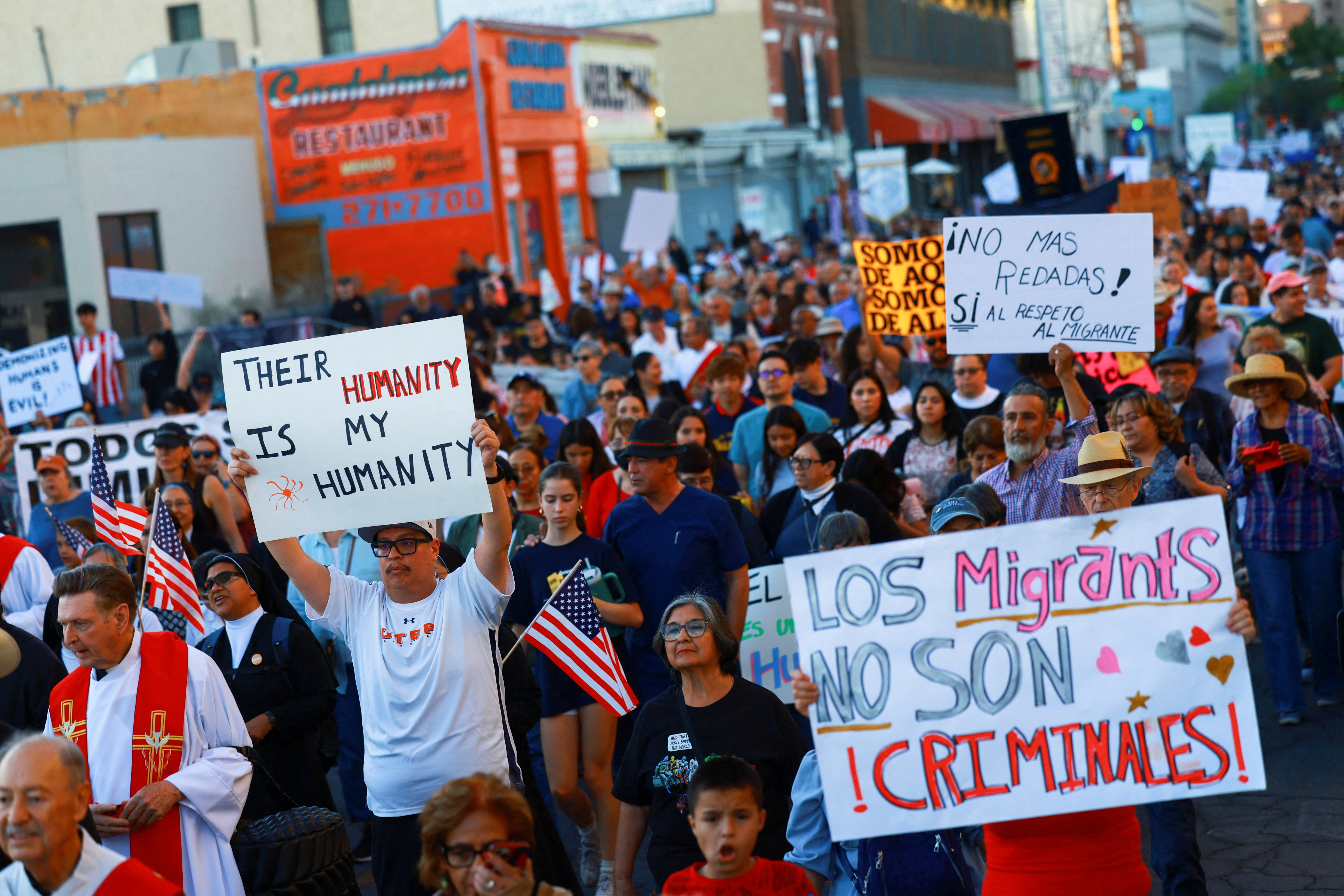 People march through street holding signs in support of immigrants