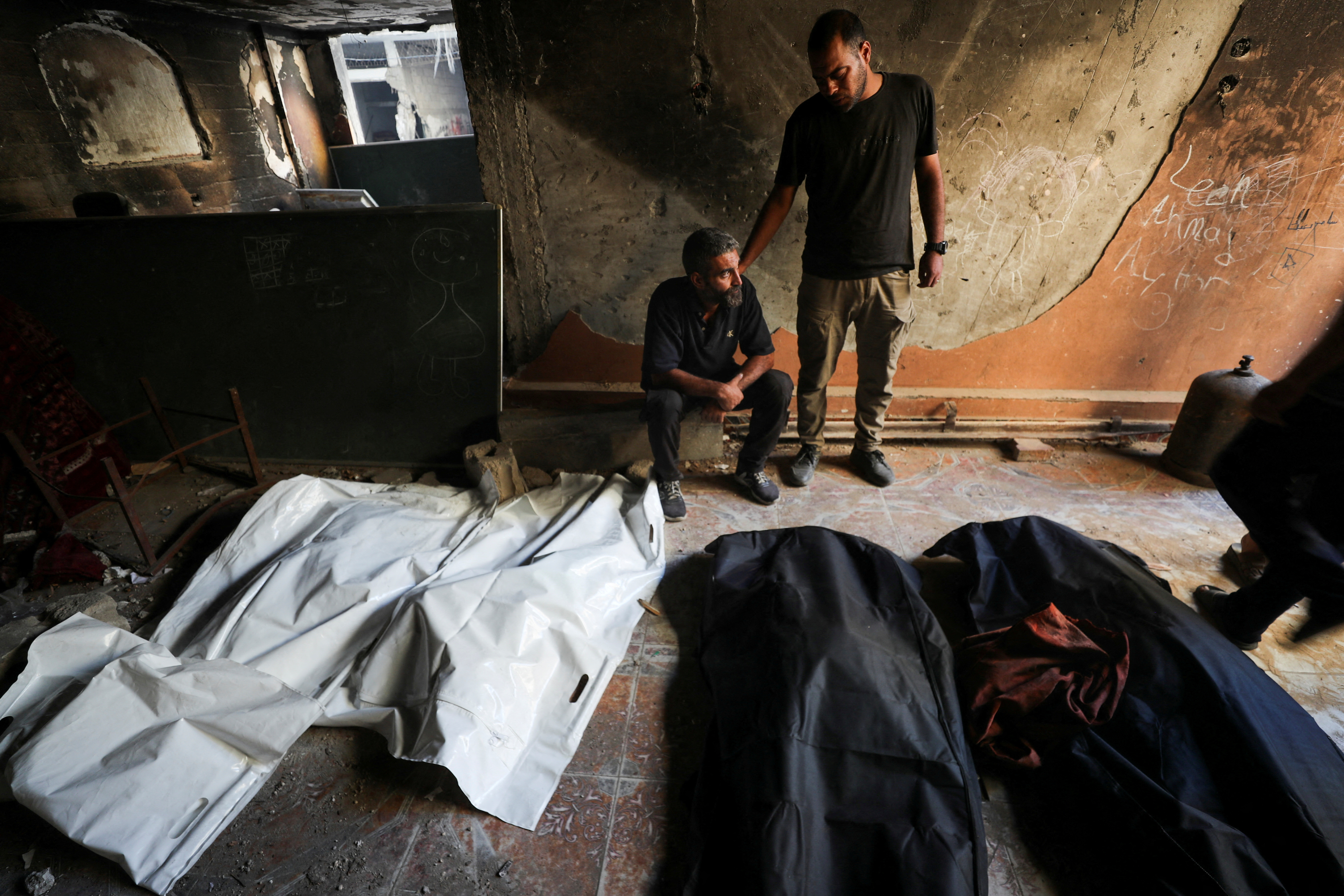 Palestinians react next to the bodies of people killed at the site of an overnight Israeli strike on a house, in Gaza City, July 6, 2025. [Mahmoud Issa/Reuters]