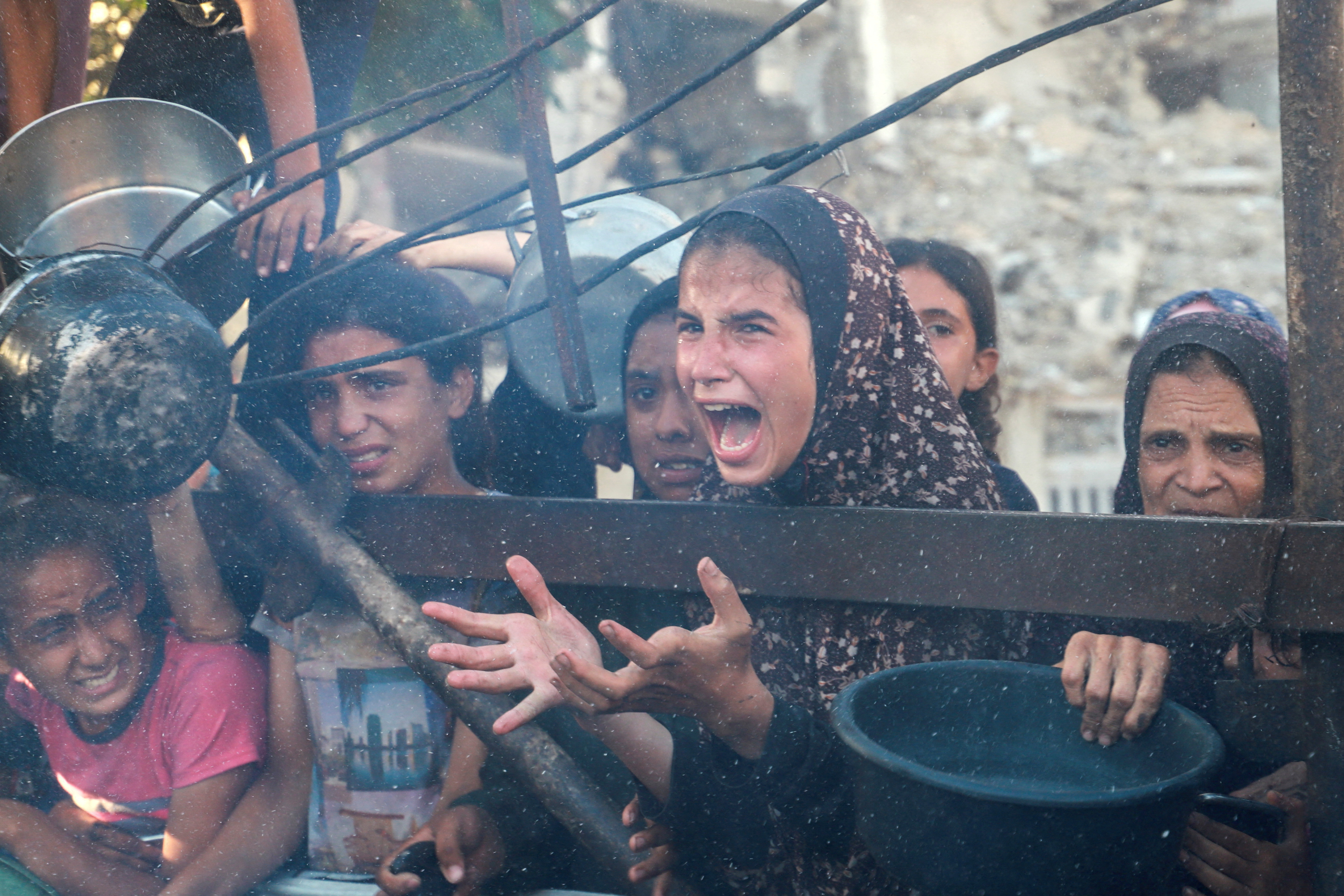 A Palestinian girl reacts as she asks for food from a charity kitchen, amid a hunger crisis, in Gaza City, July 7, 2025.