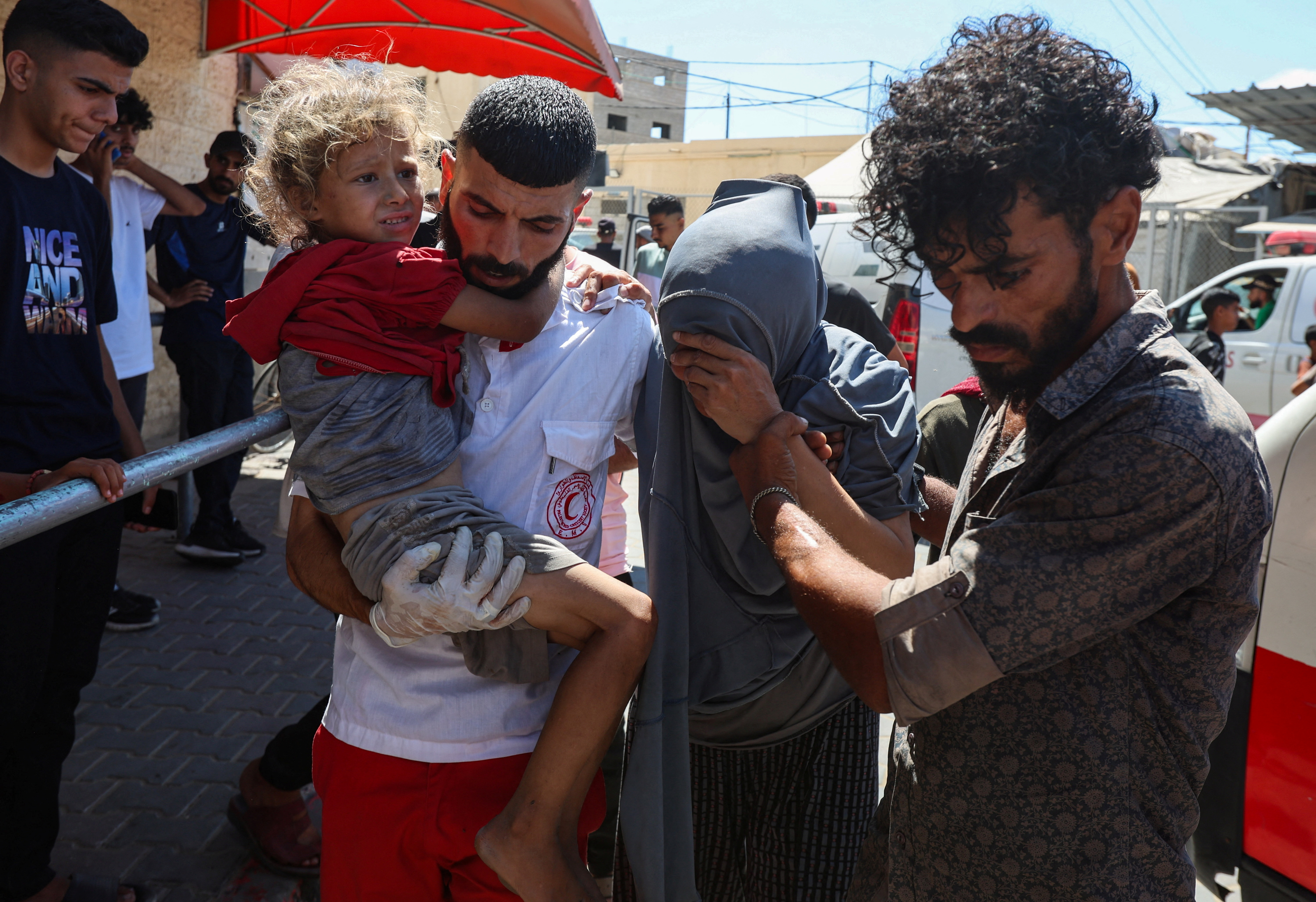 A Palestinian carries a child as wounded Palestinians receive treatment at Al-Aqsa Martyrs Hospital, after an Israeli airstrike on a house, in Deir al-Balah, central Gaza Strip