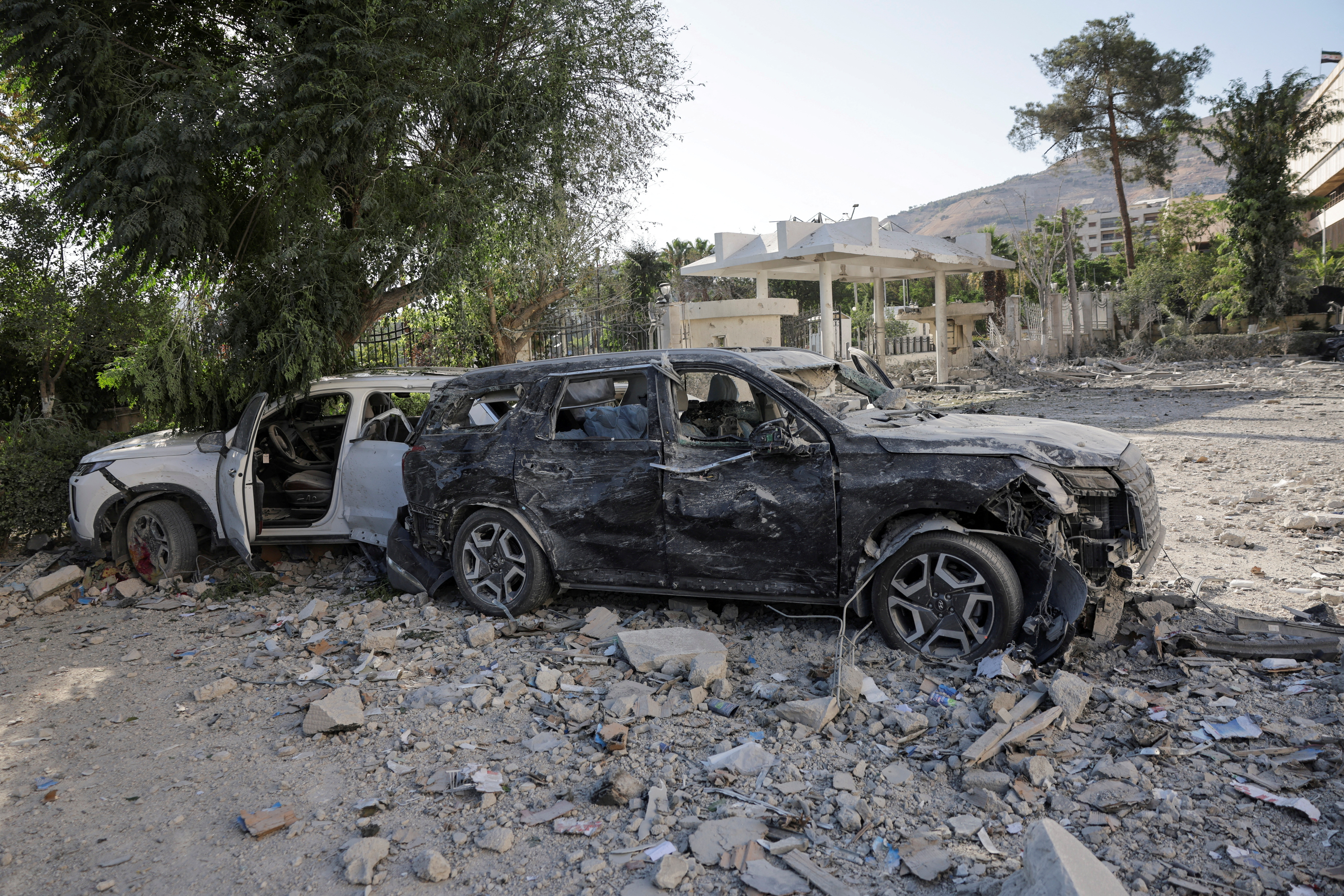 Destroyed cars sit in the street, after powerful airstrikes shook Damascus on Wednesday