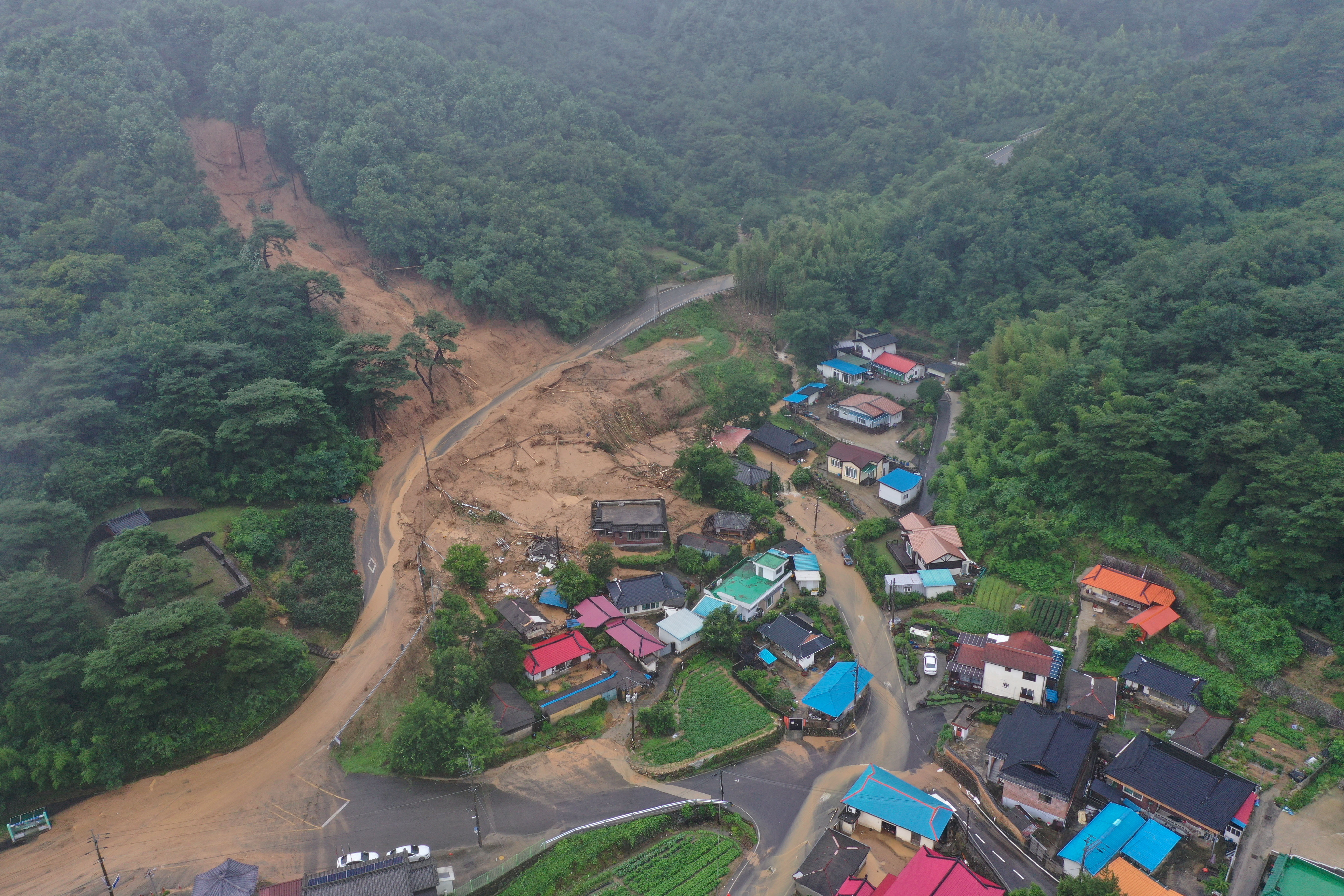 a view of a flooded village with torrents of brown water
