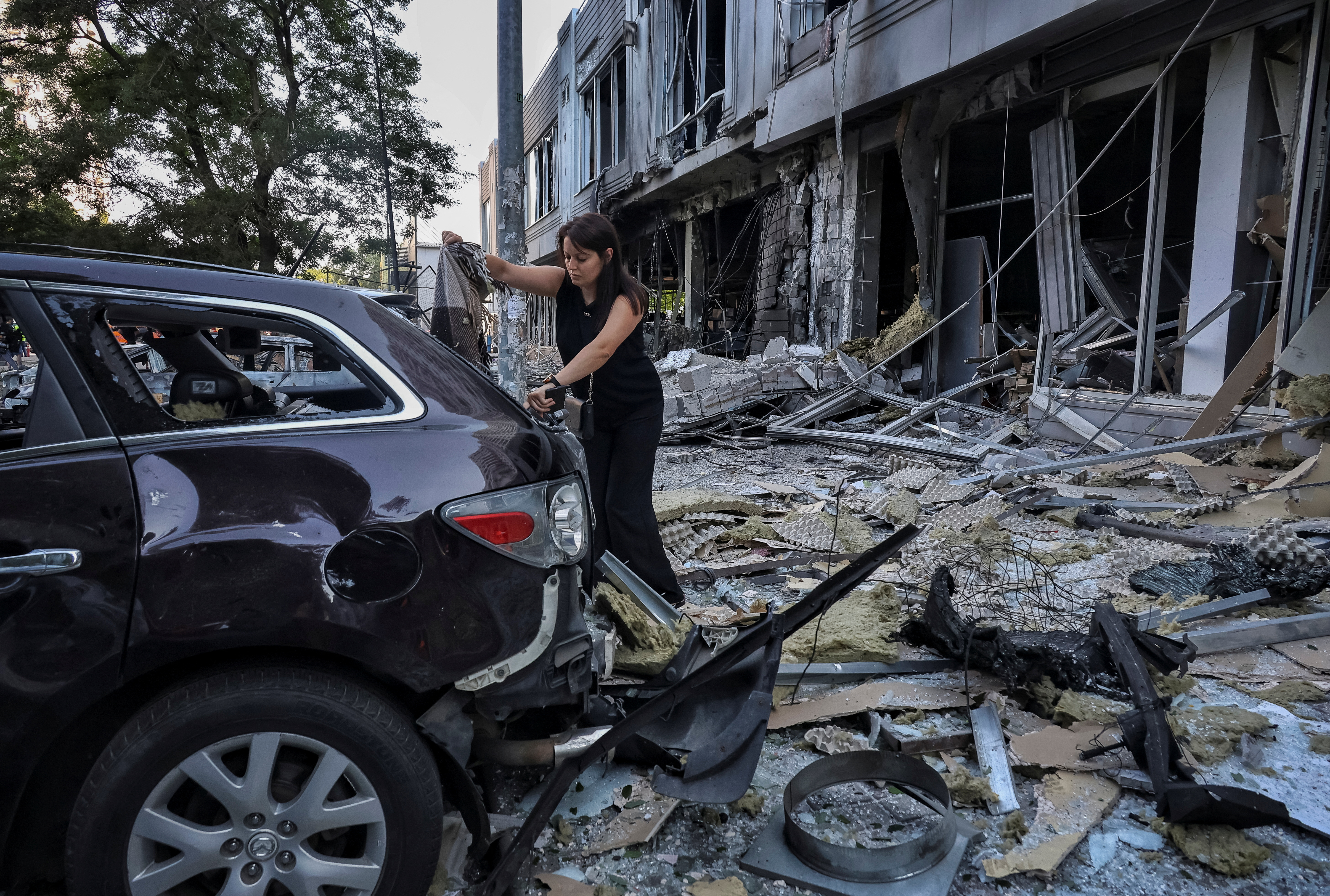 A resident inspects a damaged car at the site of the Russian drone strike in Odesa, Ukraine