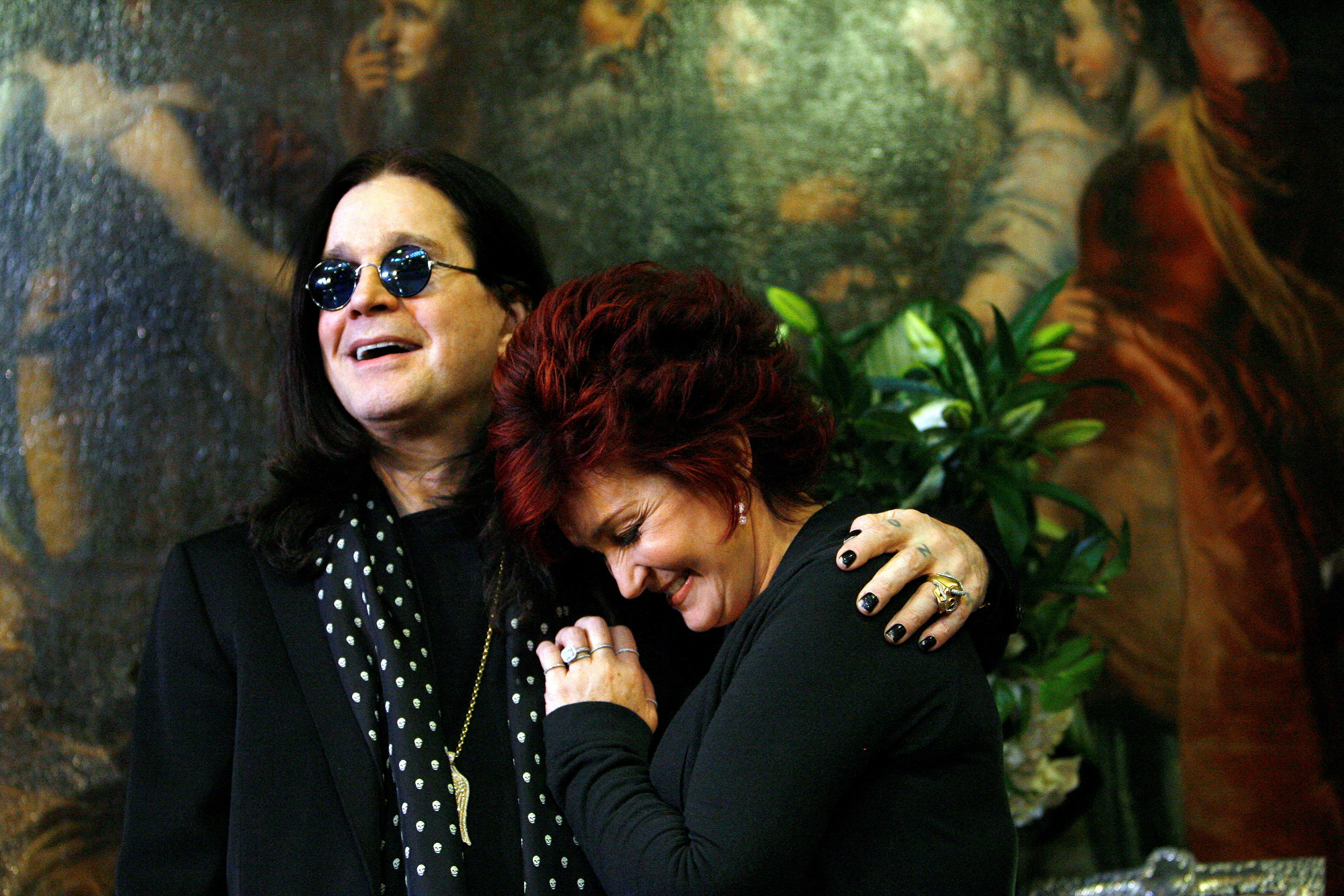 FILE PHOTO: Ozzy and Sharon Osbourne smile as they pose in front of some of their belongings to be auctioned in Beverly Hills, California, November 26, 2007. A portion of the proceeds from the two-day auction of property from the Osbourne's homes will benefit the Sharon Osbourne Colon Cancer Program.