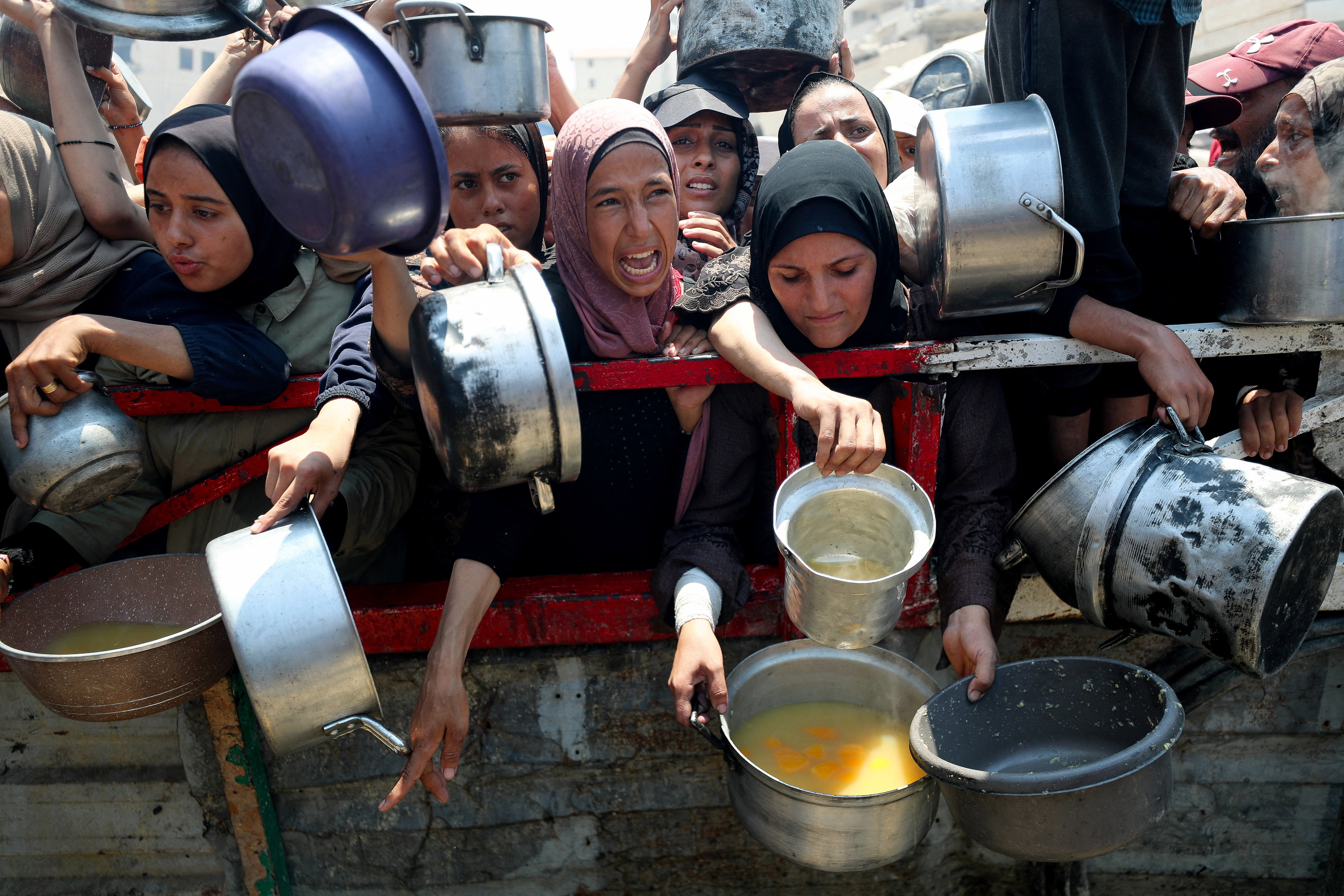 Palestinians wait to receive food from a charity kitchen