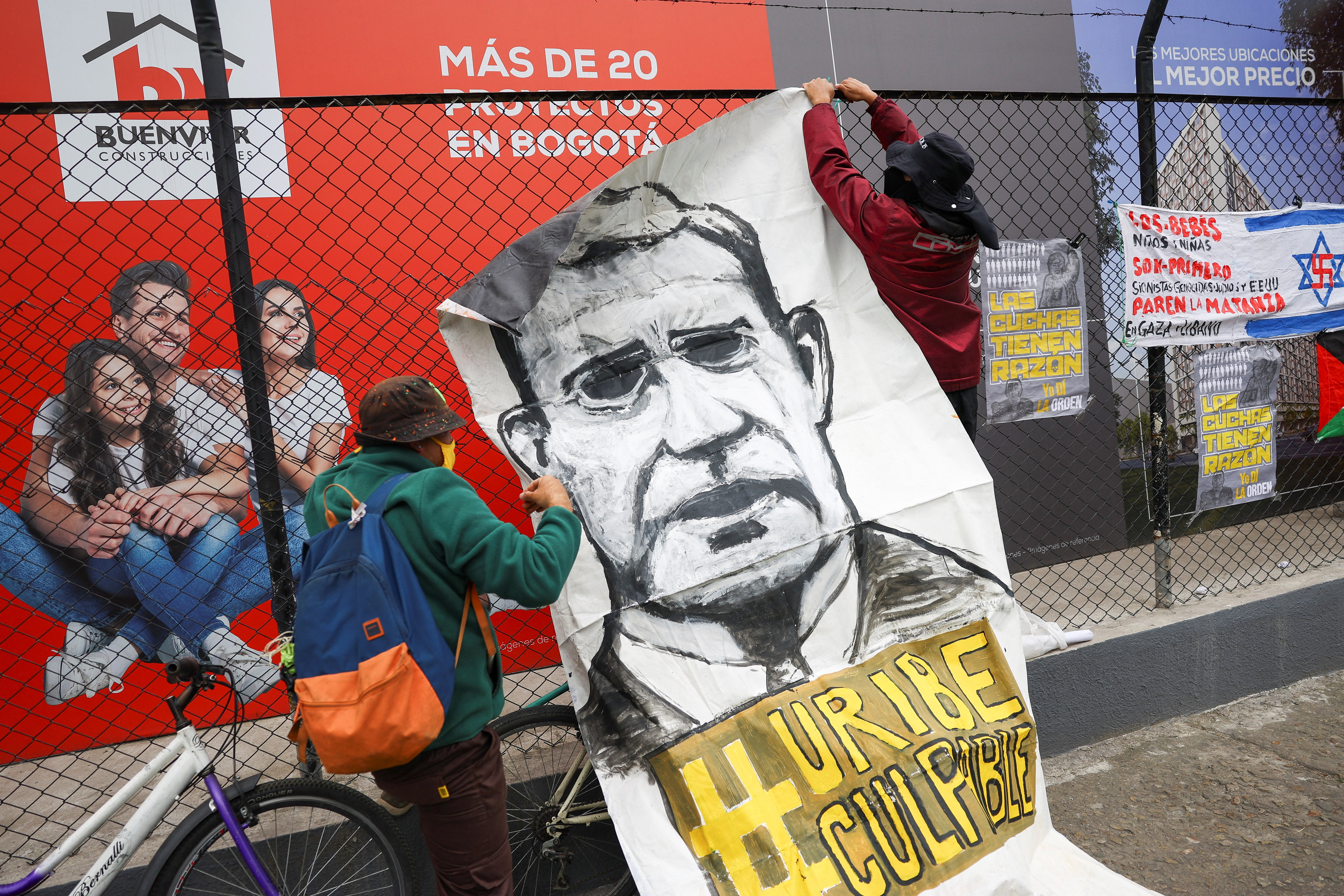 People hang a banner reading "Uribe guilty" as they protest against former Colombian President Alvaro Uribe outside the court.