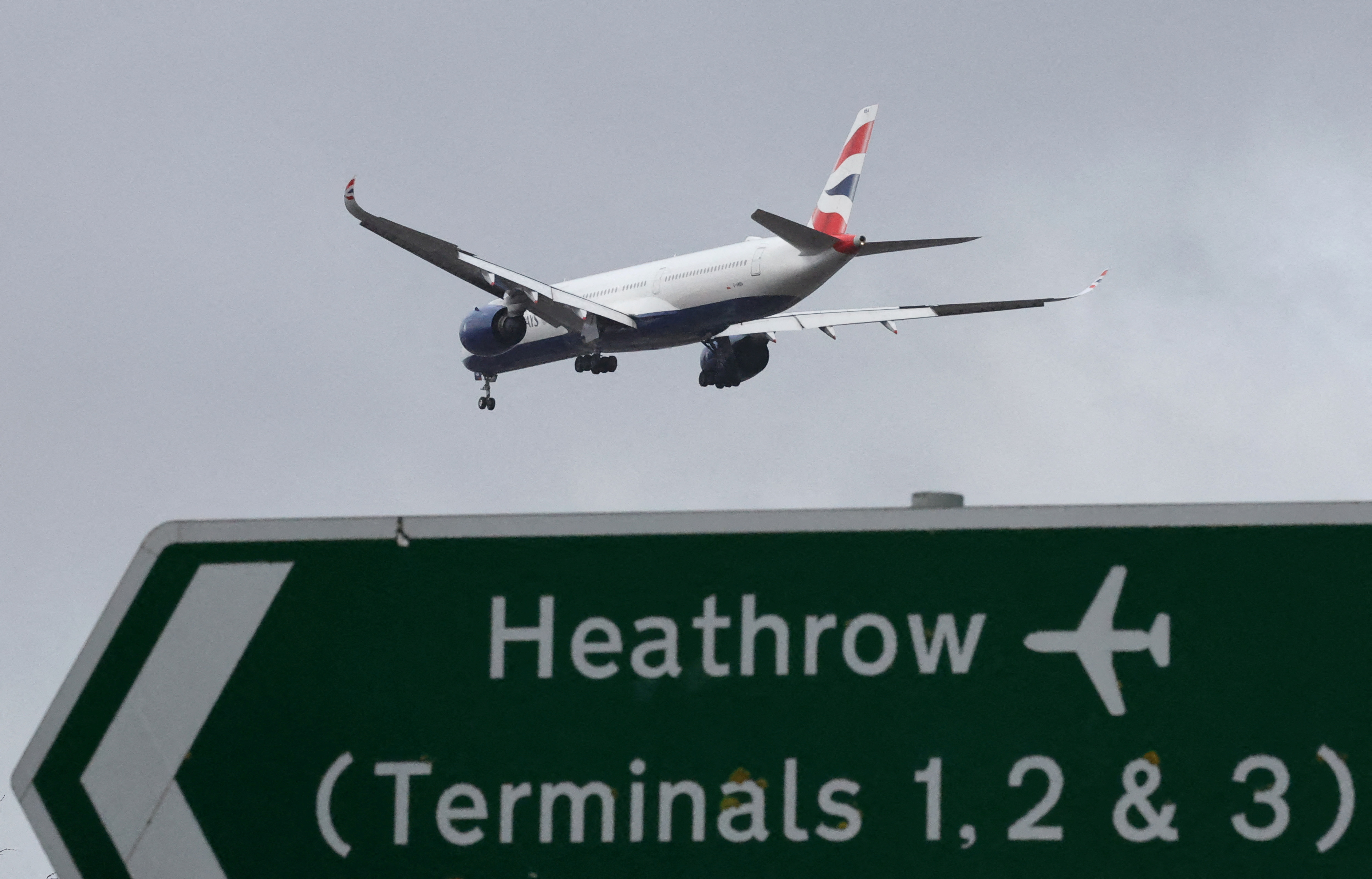A British Airways passenger plane flies over a road direction sign as it makes its landing approach to Heathrow Airport in west London, Britain, January 28, 2025. [File: Toby Melville/Reuters]