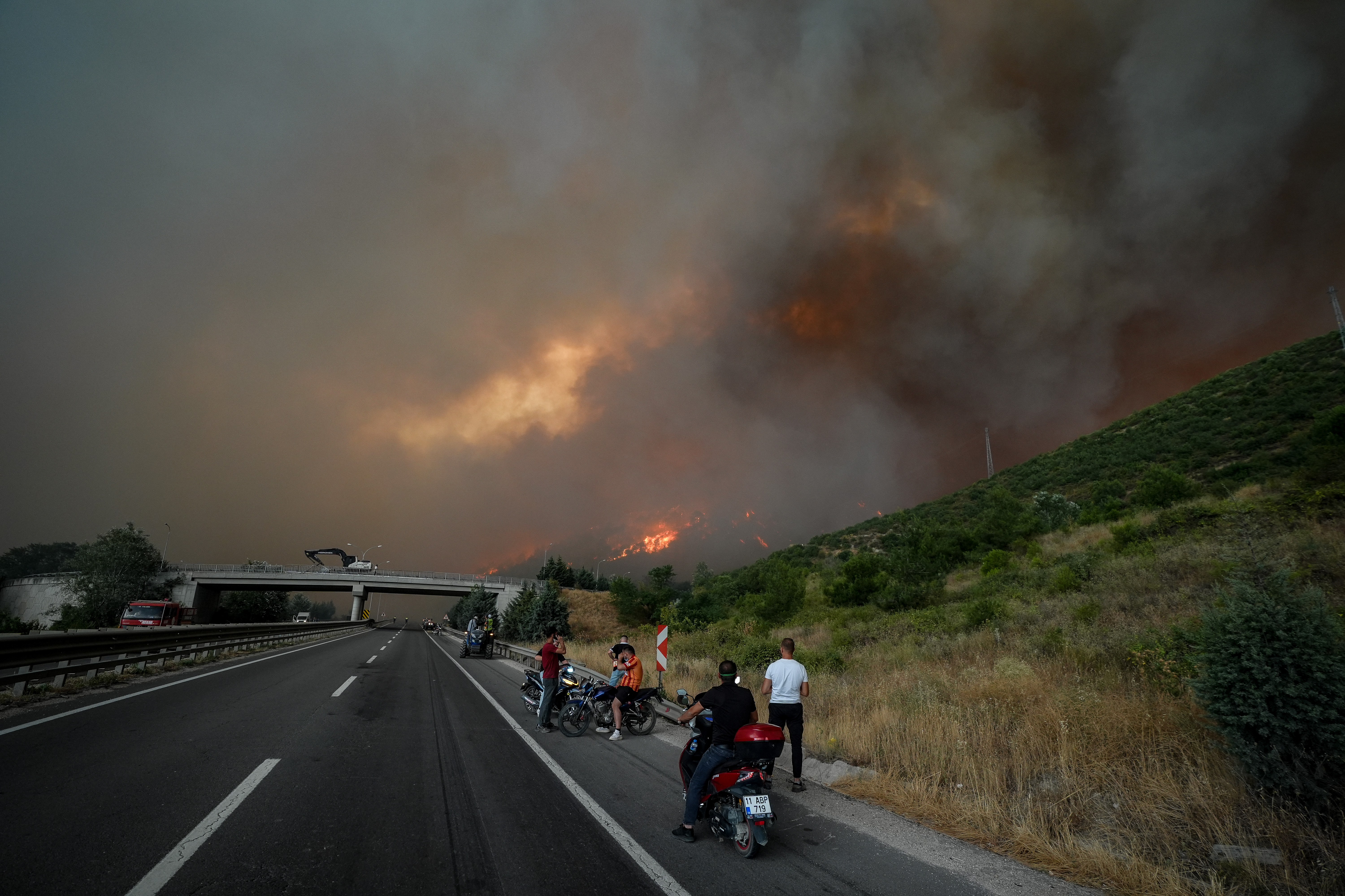 BILECIK, TURKIYE - JULY 23: Smoke and flames rise among the trees as villagers are being evacuated after a forest fire, which started in Sakarya’s Geyve district and spread to Bilecik, reignited due to strong winds after initially being brought under control, in Bilecik, Turkiye on July 23, 2025. ( Sergen Sezgin - Anadolu Agency )