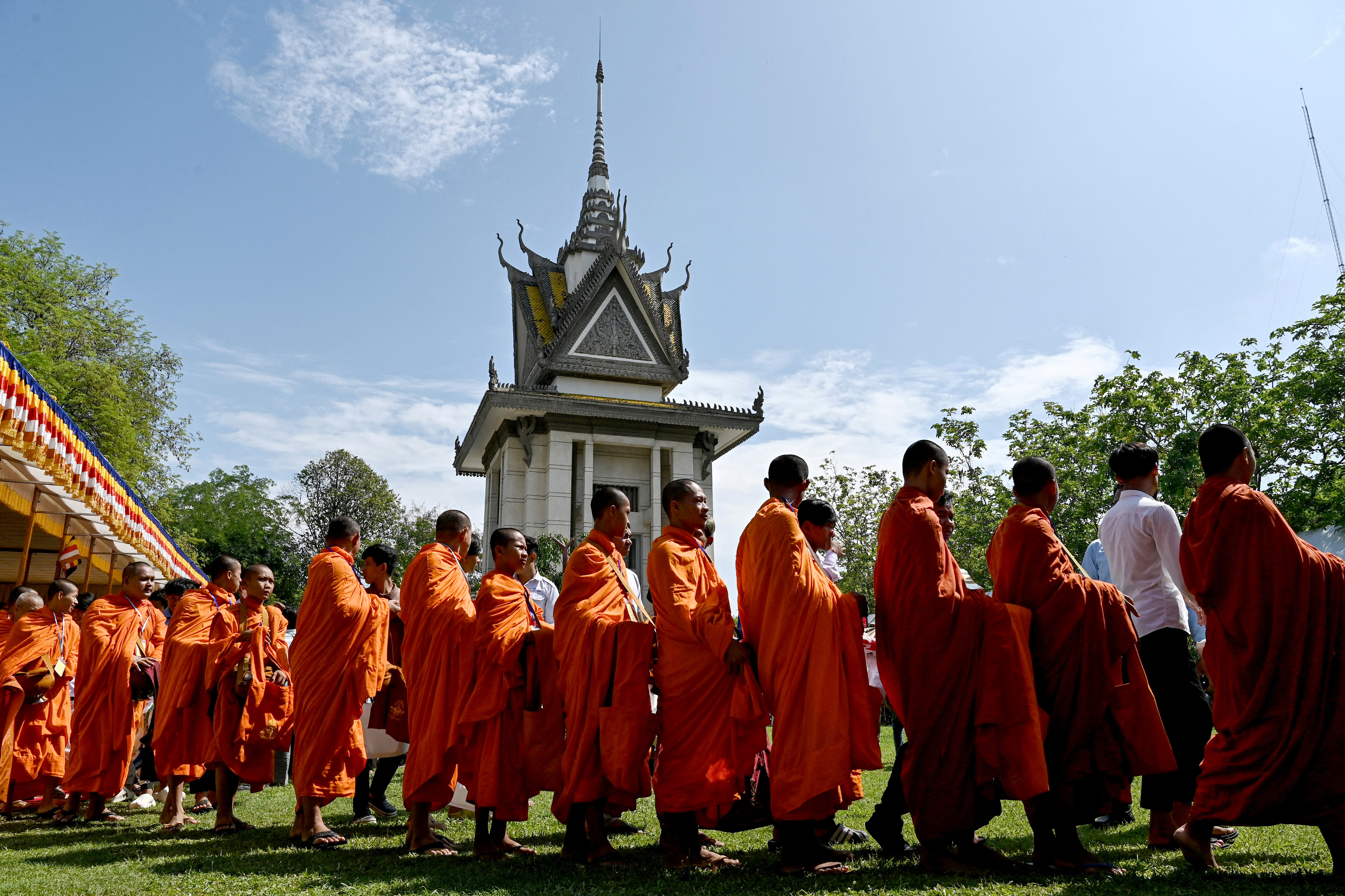 Buddhist monks line up to received food and alms during the annual 'Day of Remembrance' for the victims of the Khmer Rouge regime at the Choeung Ek memorial in Phnom Penh, Cambodia on May 20, 2025.