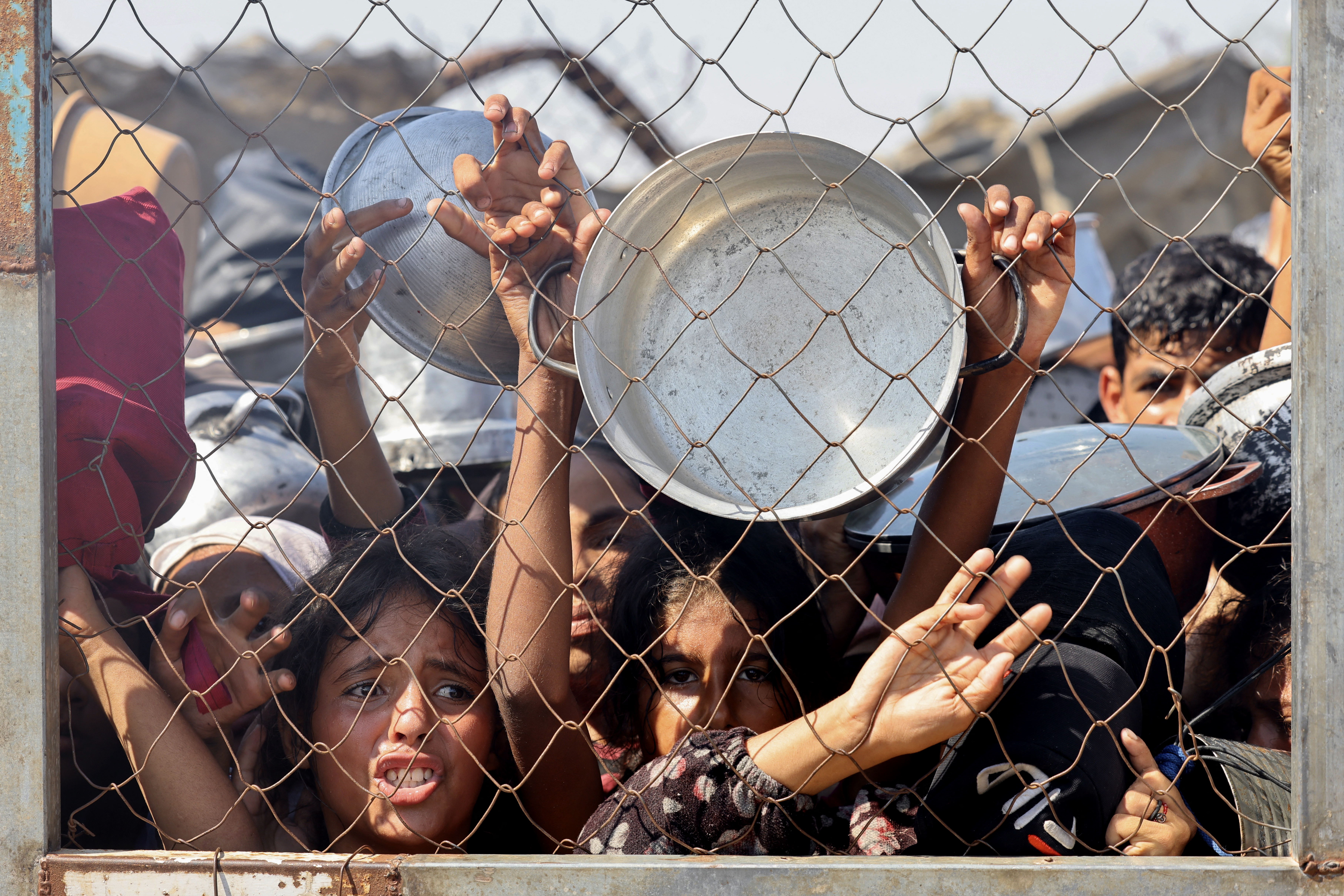 Palestinians, mostly children, push to receive a hot meal at a charity kitchen in the Mawasi area of Khan Yuni