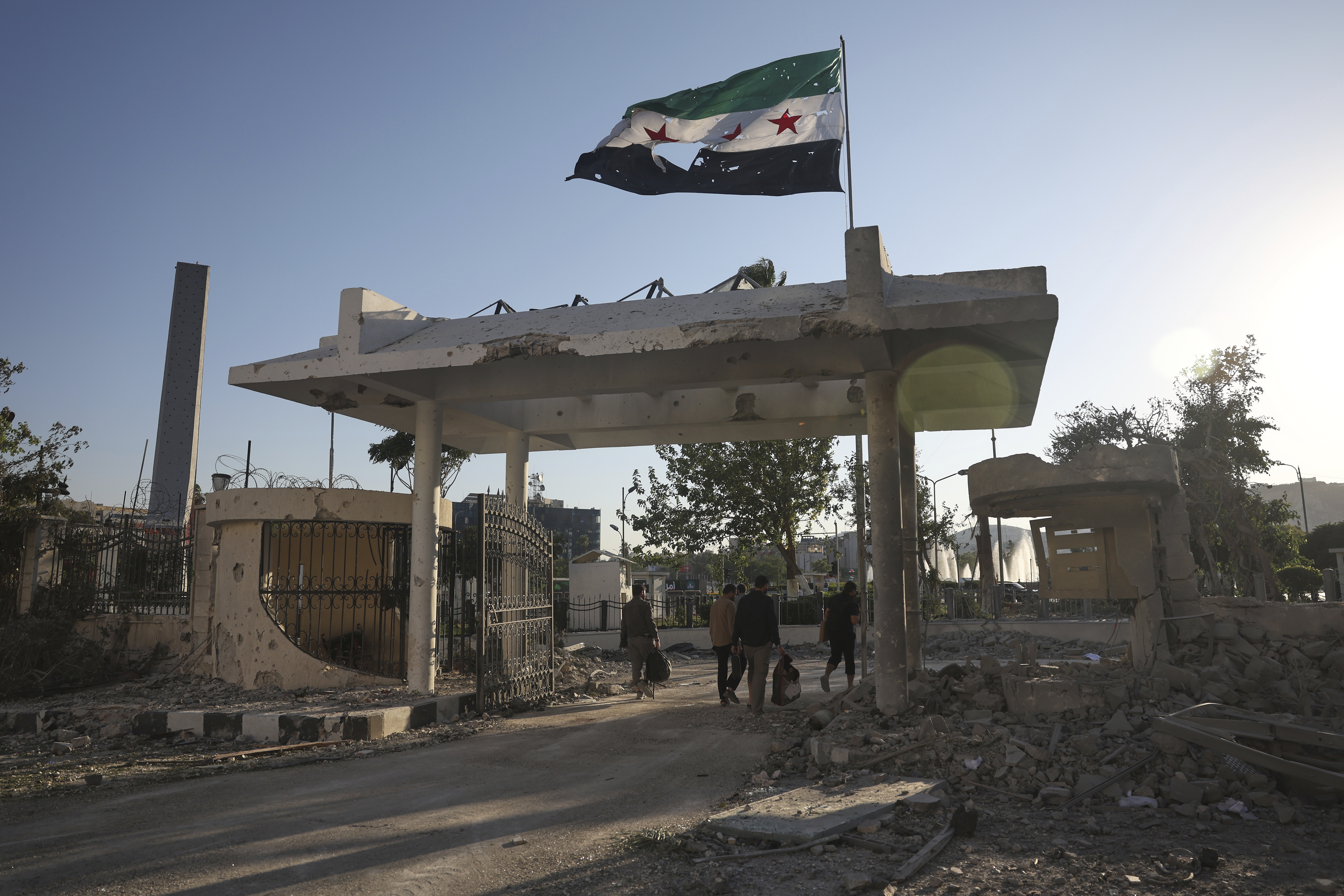 Security members carry belongings as they leave the damaged Syrian Defense Ministry
