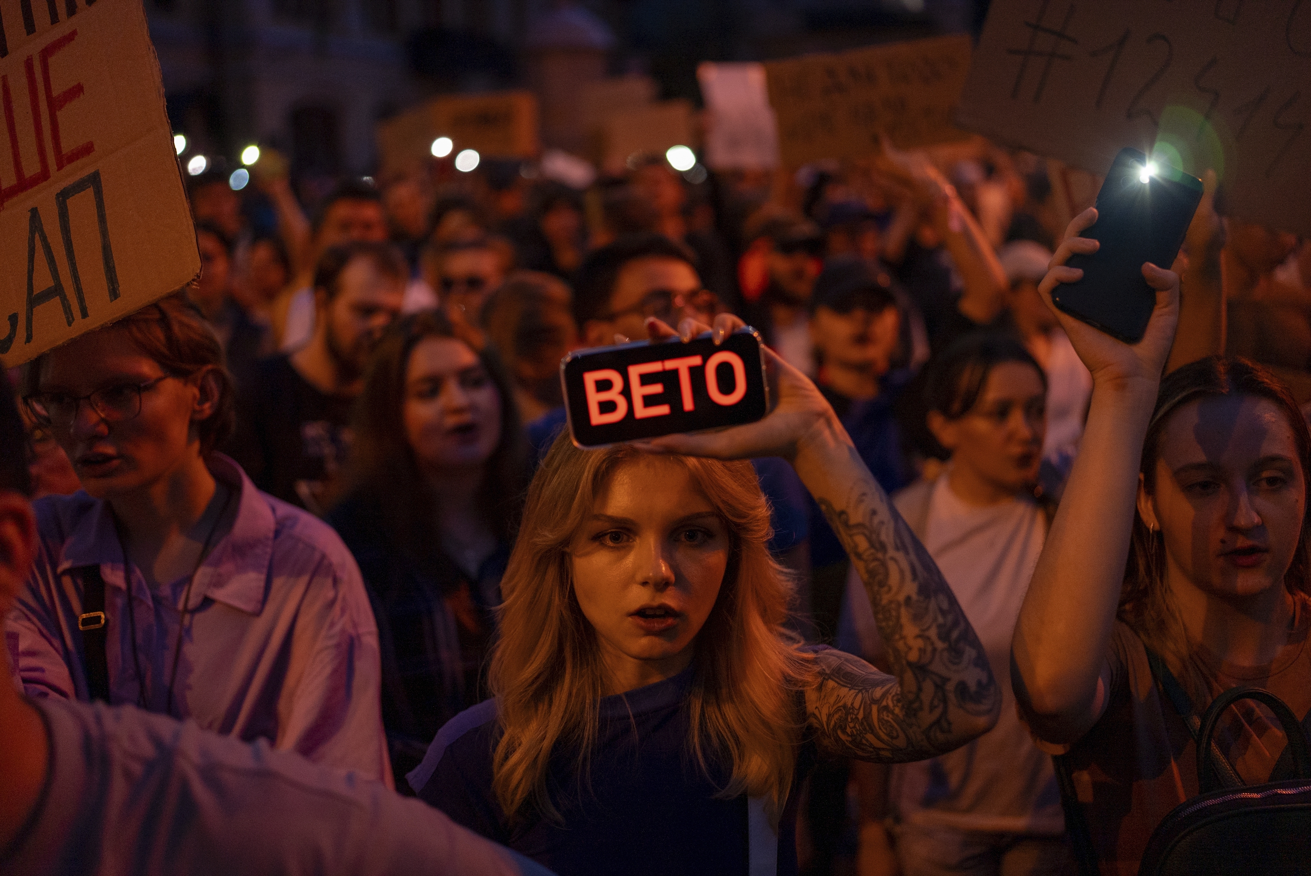 A woman holds a phone with a sign reads "Veto" during the protest against the law aimed towards regulations of anti-corruption institutions in central Kyiv, Ukraine, Tuesday, July 22, 2025.