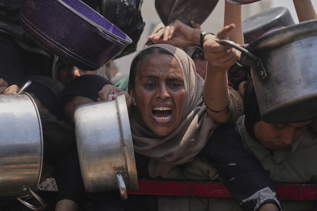 Palestinians try to get food at a charity kitchen in Gaza