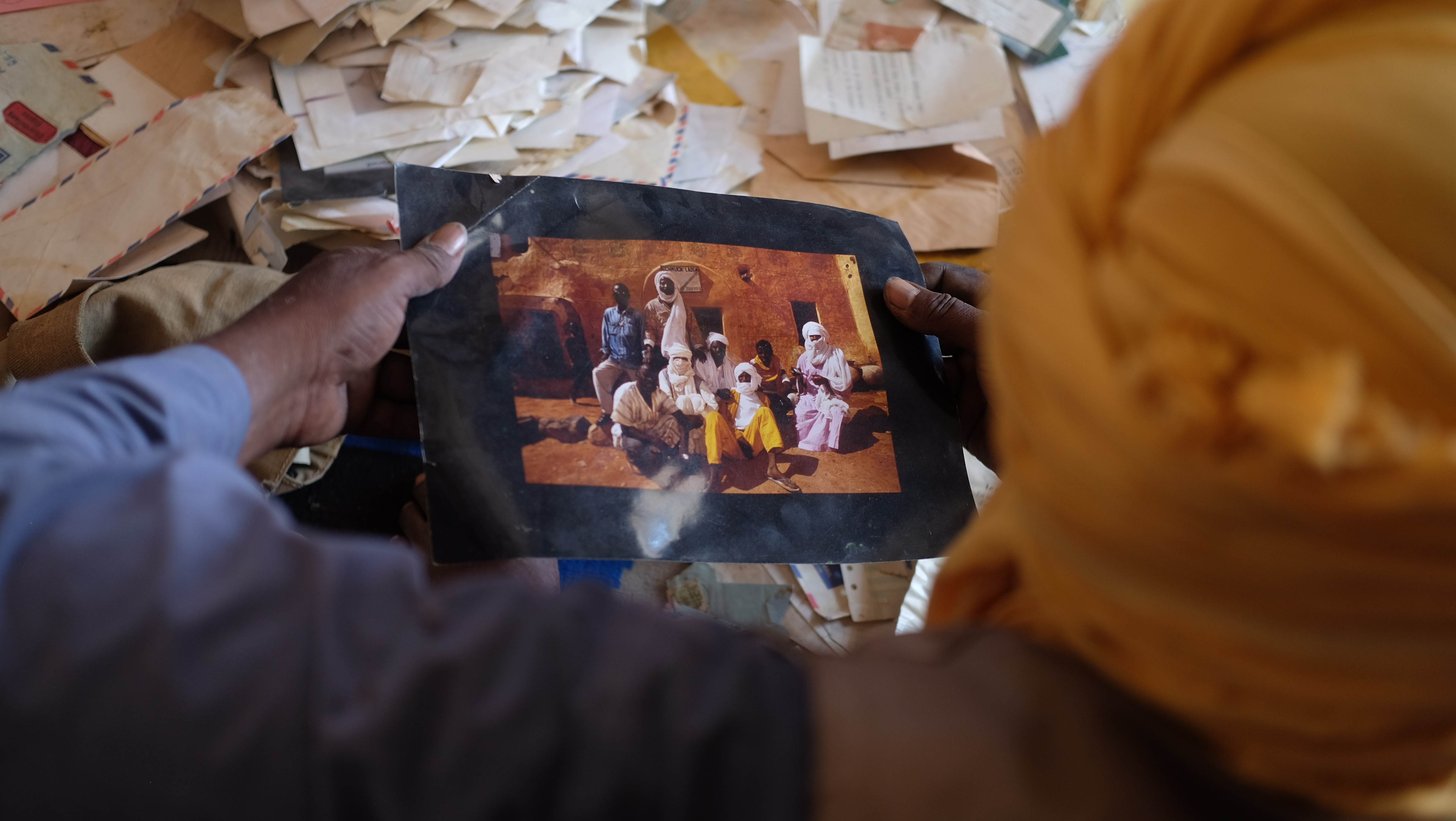 Illo holds an old photo showing him and his friends in front of his old store