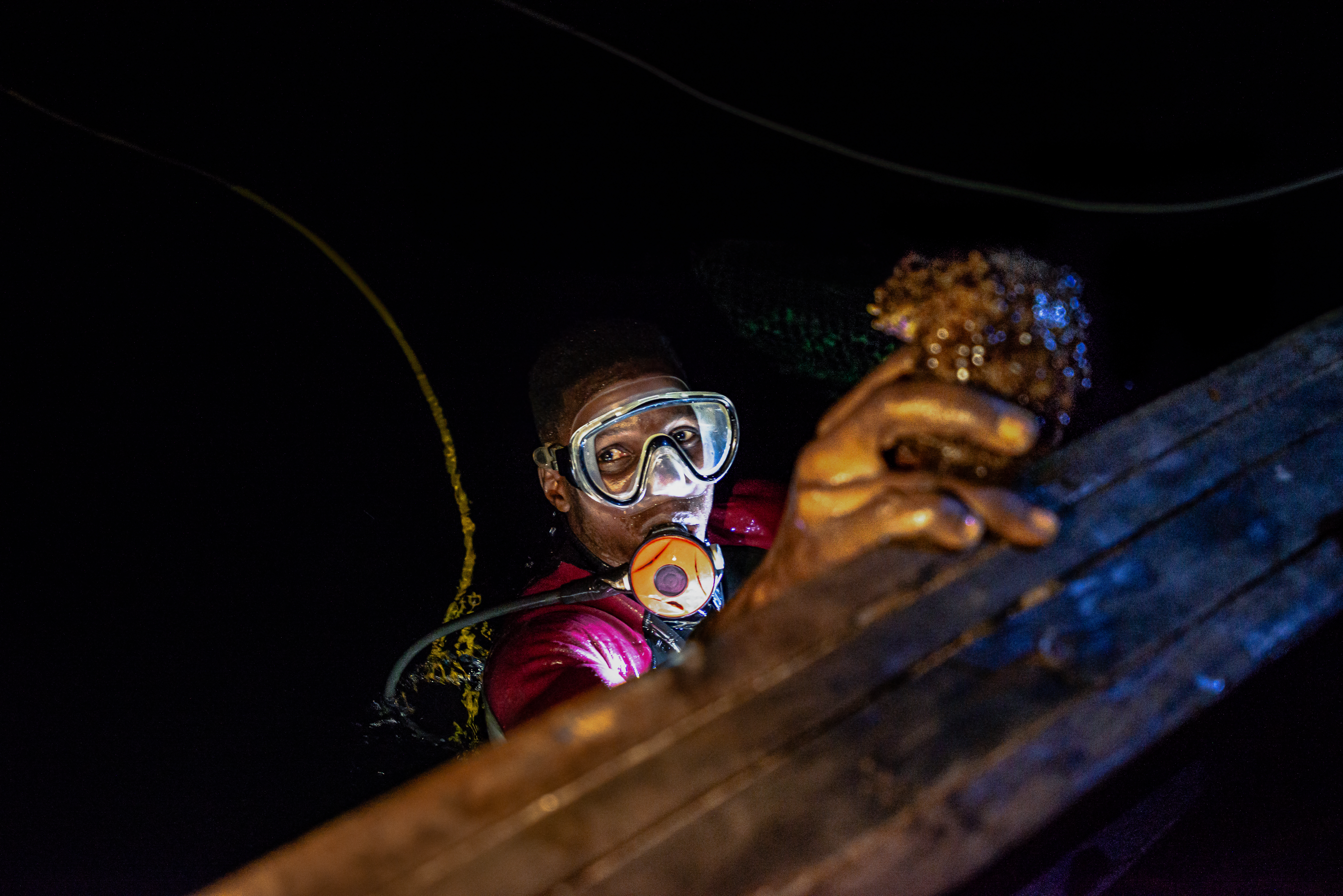 Olomode Jones wearing goggles and holding a sea cucumber.