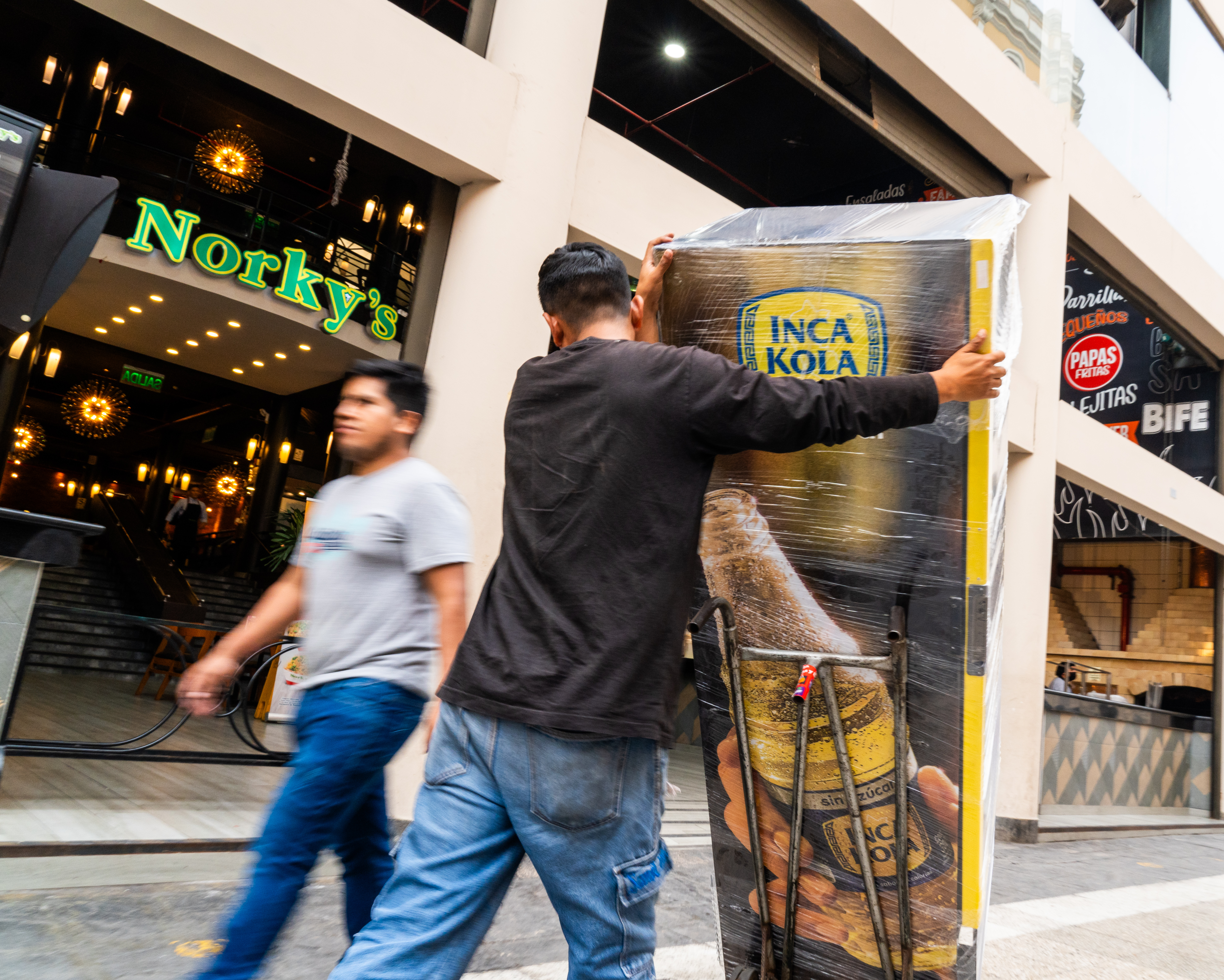 Workers deliver an Inca Kola machine to a business in Lima, Peru.