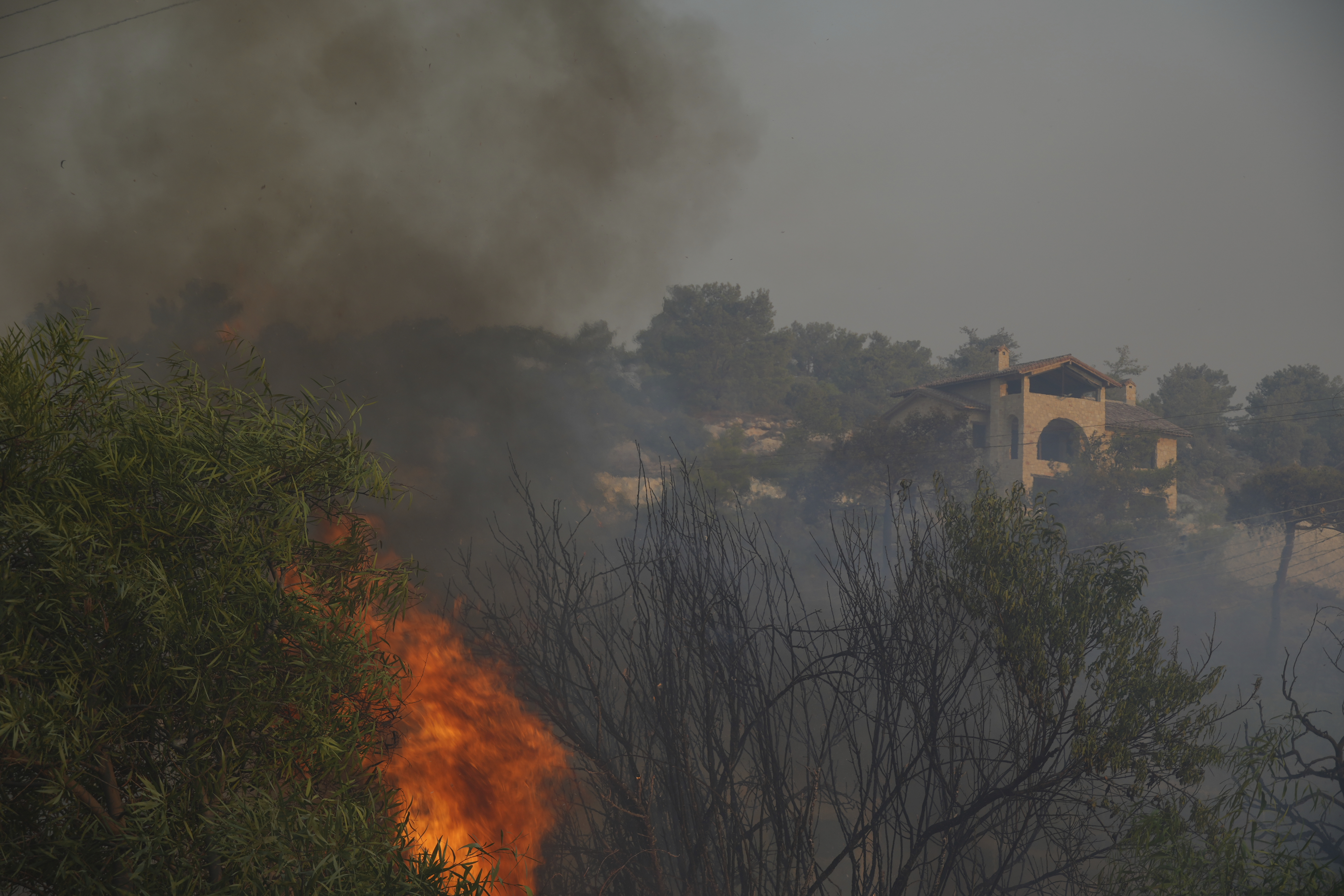Flames burn near a house in Souni village, Cyprus, during a massive wildfire on the southern side of the east Mediterranean island nation's Troodos mountain range, Thursday, July 24, 2025. (AP Photo/Petros Karadjias)