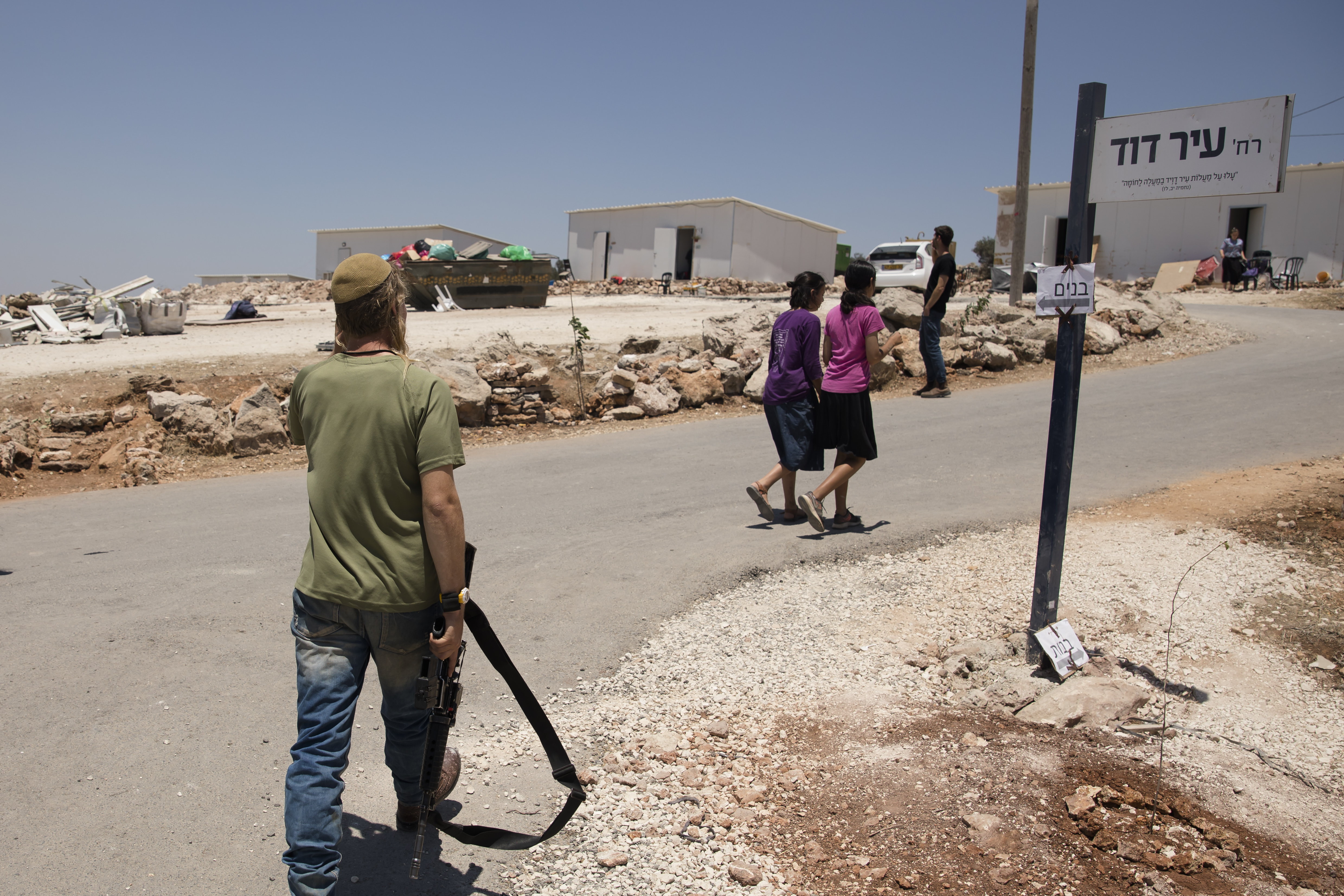 Israeli settler walks with a rifle at a settlement outpost.