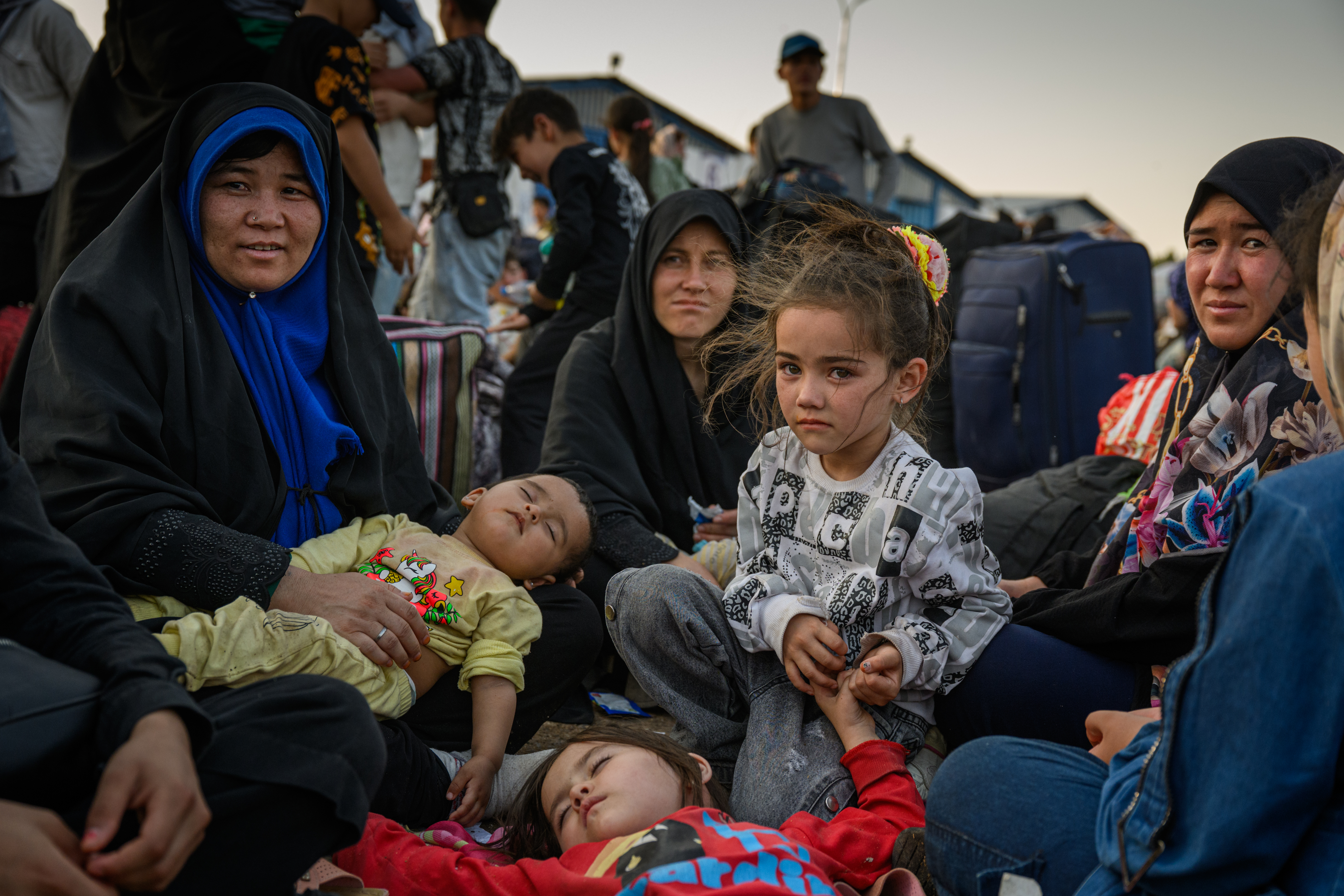 ISLAM QALA, AFGHANISTAN – JULY 2: Farahnaz, 5, waits for assistance with her family which was recently deported from Iran, with the few belongings they were able to bring with them, on July 2, 2025, in Islam Qala, Afghanistan. With no permanent home to return to, many returnees are desperate for help but NGOs and UN agencies are unable to provide enough. According to the UN’s International Organization for Migration (IOM), more than 256,000 Afghans returned from Iran last month ahead of a July 6 deadline for undocumented migrants to leave. Returnee numbers surged, hitting a peak of 43,000 in a single day on July 1. UN agencies and NGOs have warned that critical funding shortfalls are hampering aid efforts at the overwhelmed border. The number of Afghans in Iran had grown significantly since the Taliban regained control in 2021, but recent forced returns—fueled in part by the ongoing conflict between Israel and Iran—are straining humanitarian resources. Aid organizations inside Afghanistan are also struggling due to cuts in foreign funding, including the suspension of key USAID programs. (Photo by Elise Blanchard/Getty Images)