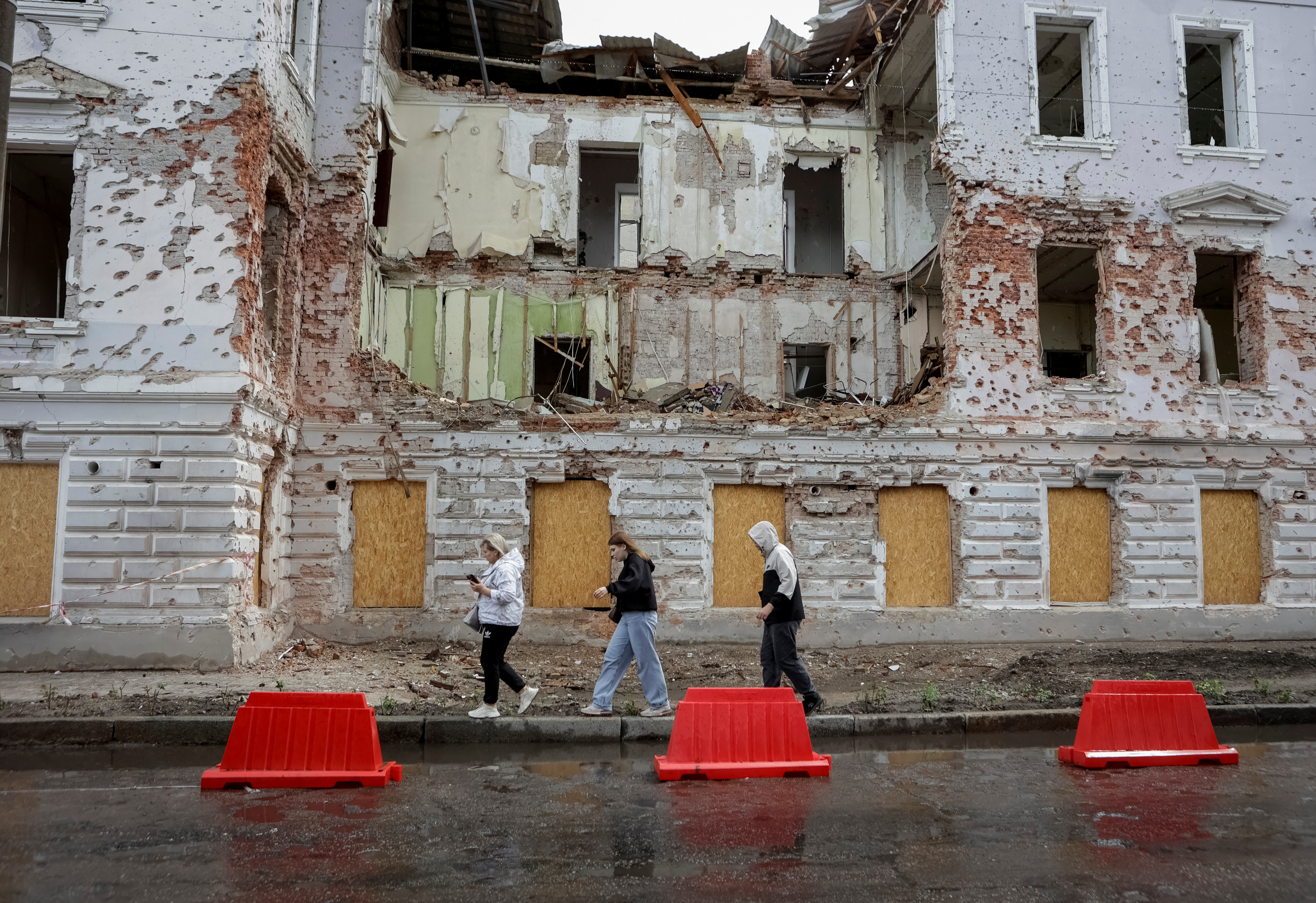 Residents walk at a street near a building damaged by Russian missile strikes, amid Russia's attack on Ukraine, in Sumy, Ukraine June 13, 2025. REUTERS/Sofiia Gatilova