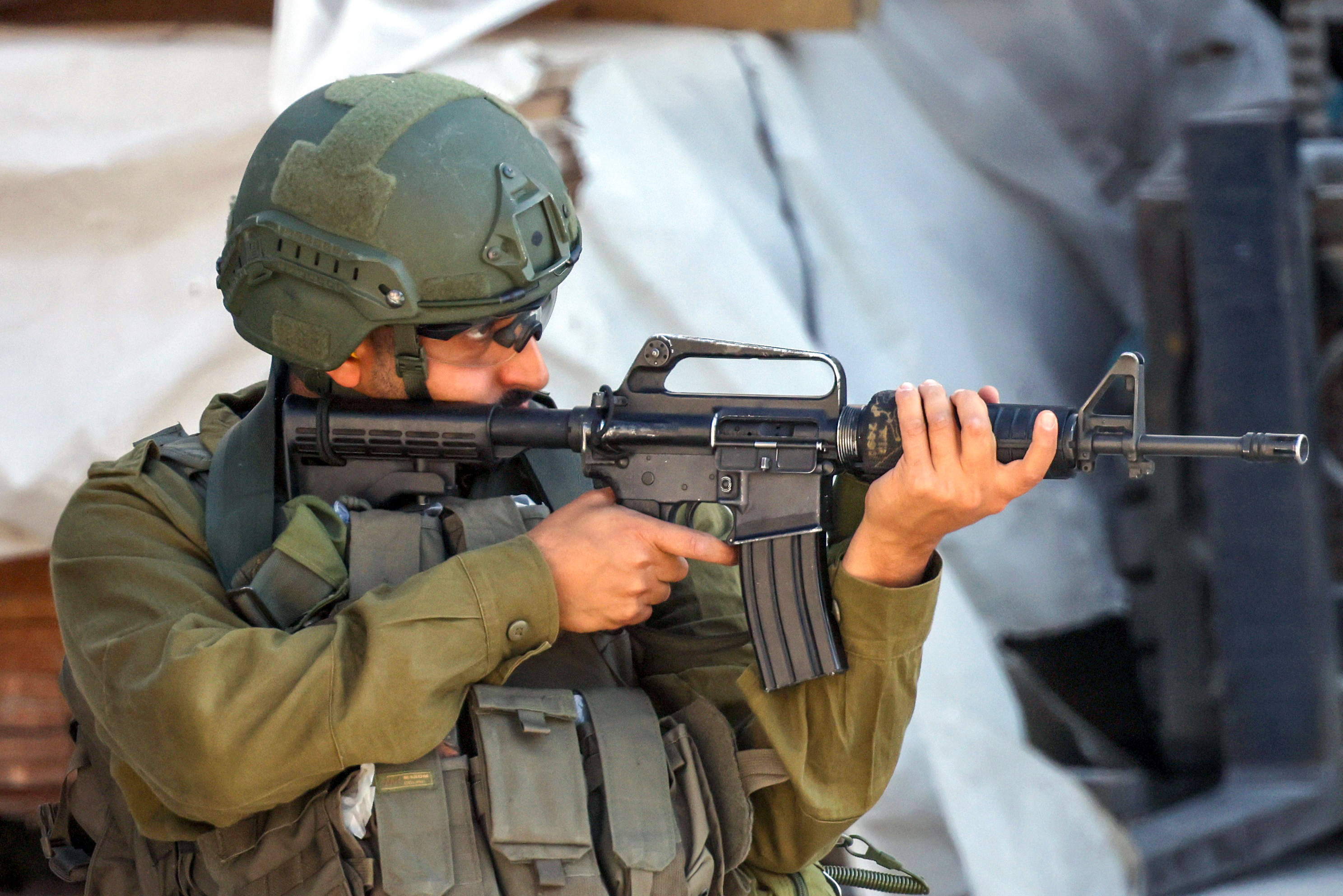 epa12210802 An Israeli soldier aims his weapon during a military raid in the West Bank city of Nablus, 02 July 2025. EPA/ALAA BADARNEH
