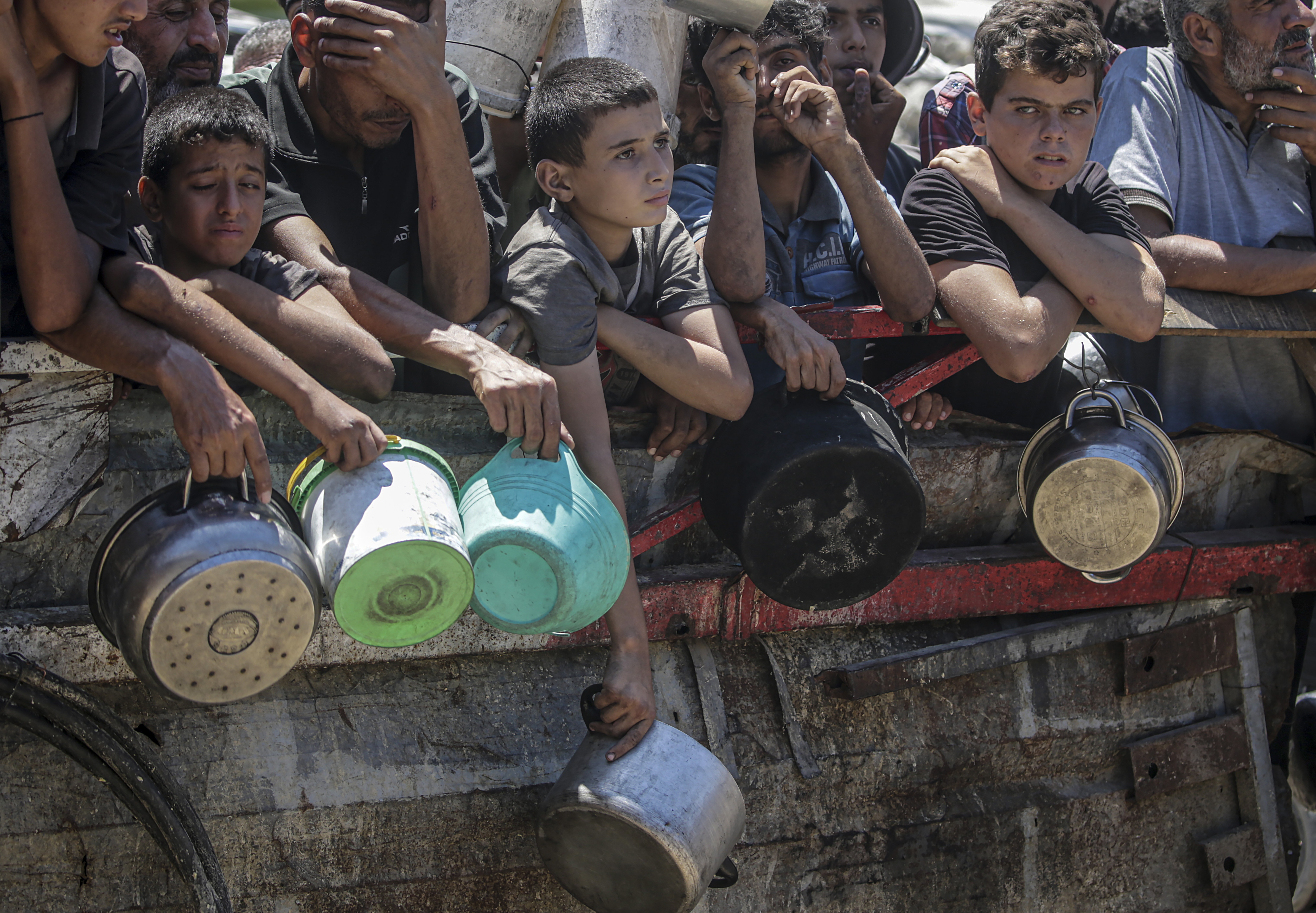 Internally displaced Palestinians, including children, hold pots as they gather to receive food from a charity kitchen in Gaza City, the Gaza Strip on August 4, 2025 [File: Mohammed Saber/EPA]