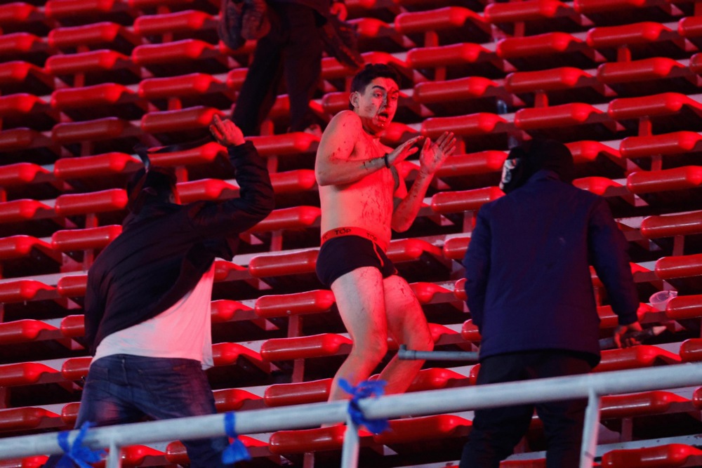 Fans clash in the stands during the CONMEBOL Copa Sudamericana round of 16 soccer match between Independiente and Universidad de Chile, in Avellaneda, Argentina