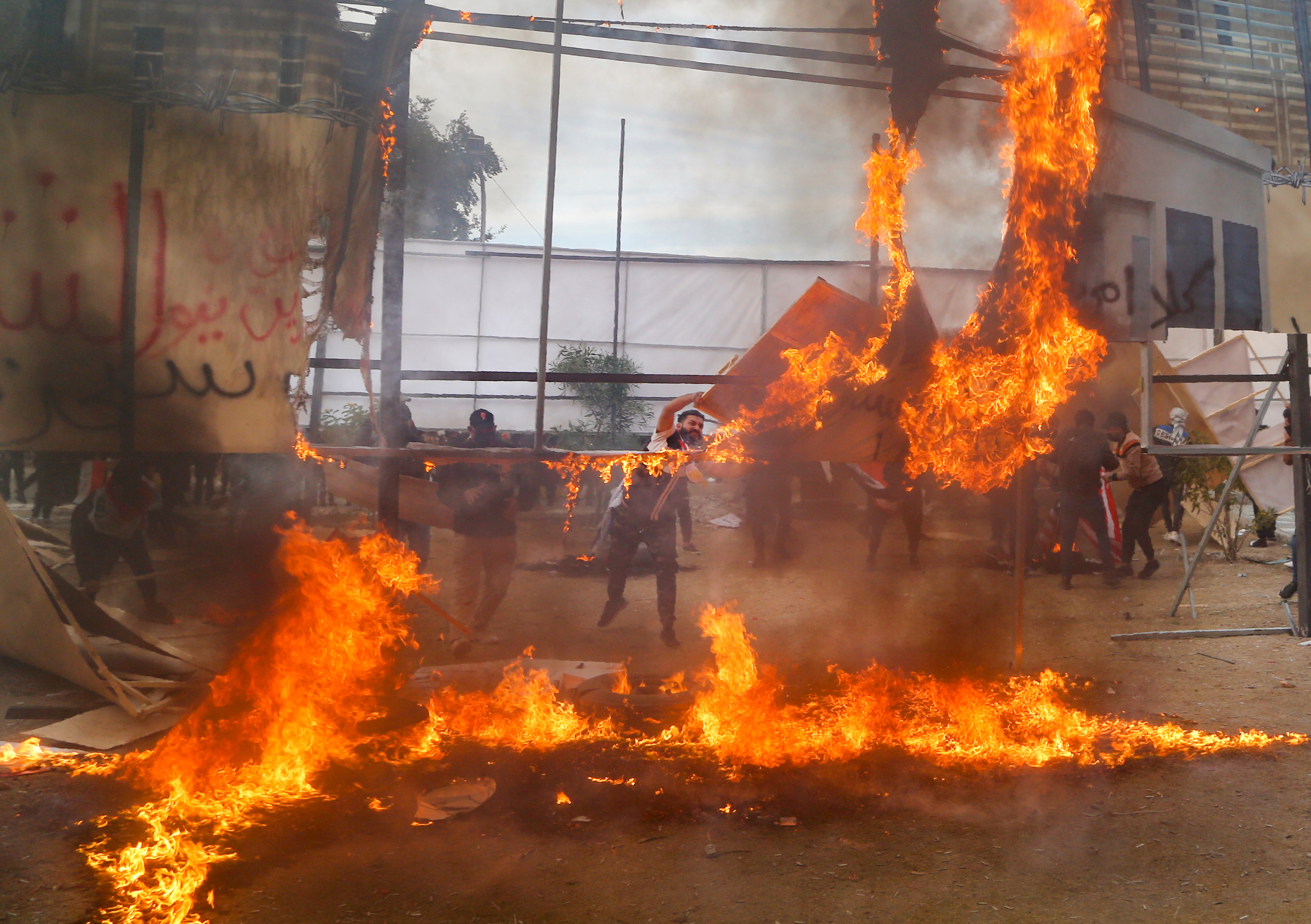 Supporters of Hashd al-Shaabi (Popular Mobilization Forces) burn a large printed image of the U.S. Embassy, to mark the anniversary of the killing of Iranian military commander General Qassem Soleimani and Iraqi militia commander Abu Mahdi al-Muhandis in a U.S. drone attack, in Baghdad, Iraq December 31, 2021. REUTERS/Ahmed Saad