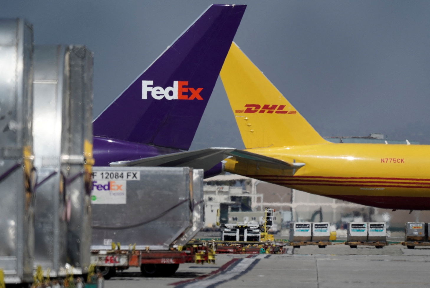 A cargo aircraft in DHL livery passes near a FedEx livery plane parked at a FedEx regional hub, at Los Angeles International Airport (LAX) in Los Angeles, California, U.S., September 16, 2022. REUTERS/Bing Guan
