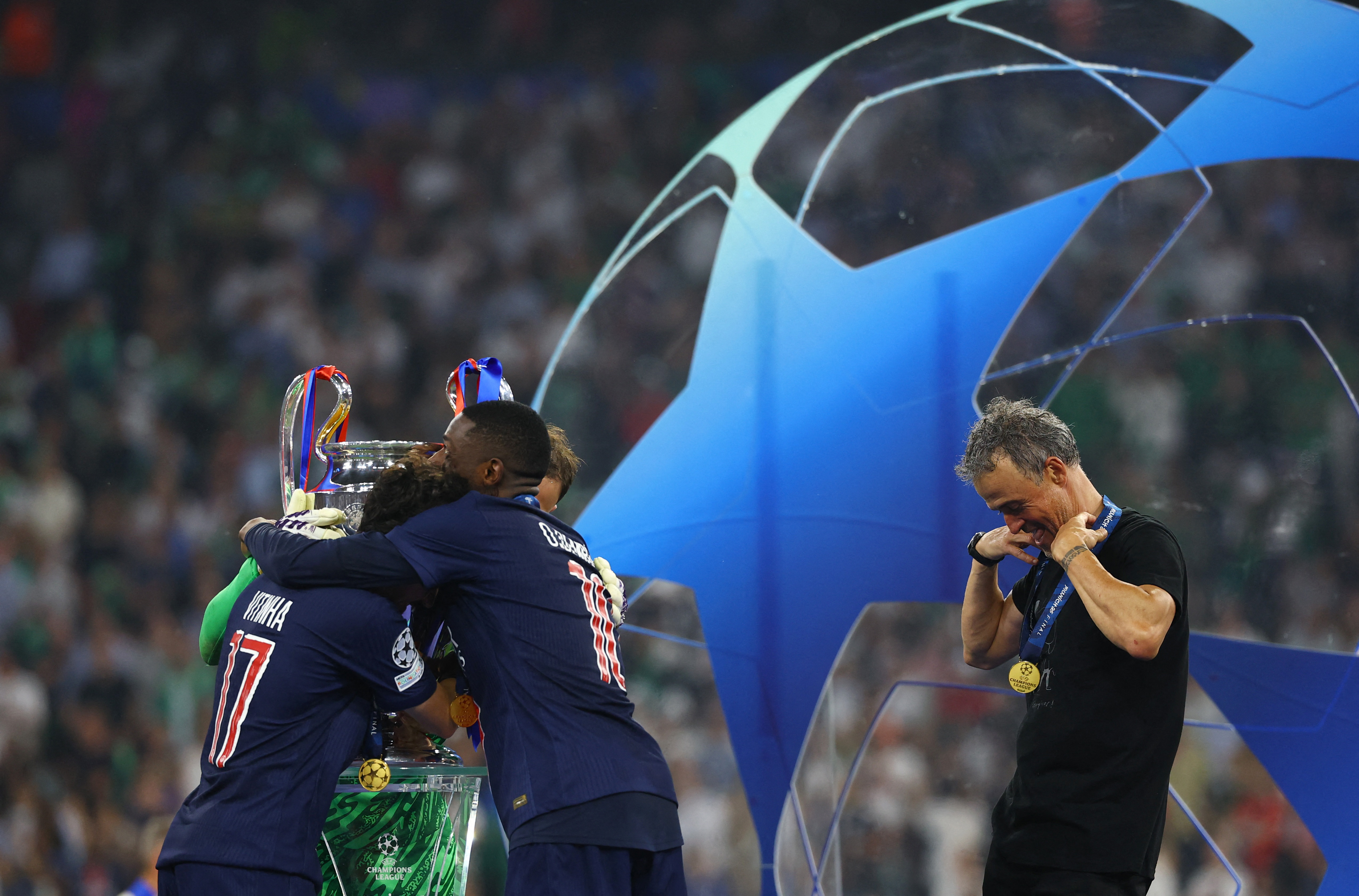 Paris Saint-Germain coach Luis Enrique, Ousmane Dembele and Nuno Mendes celebrate with the trophy after winning the Champions League