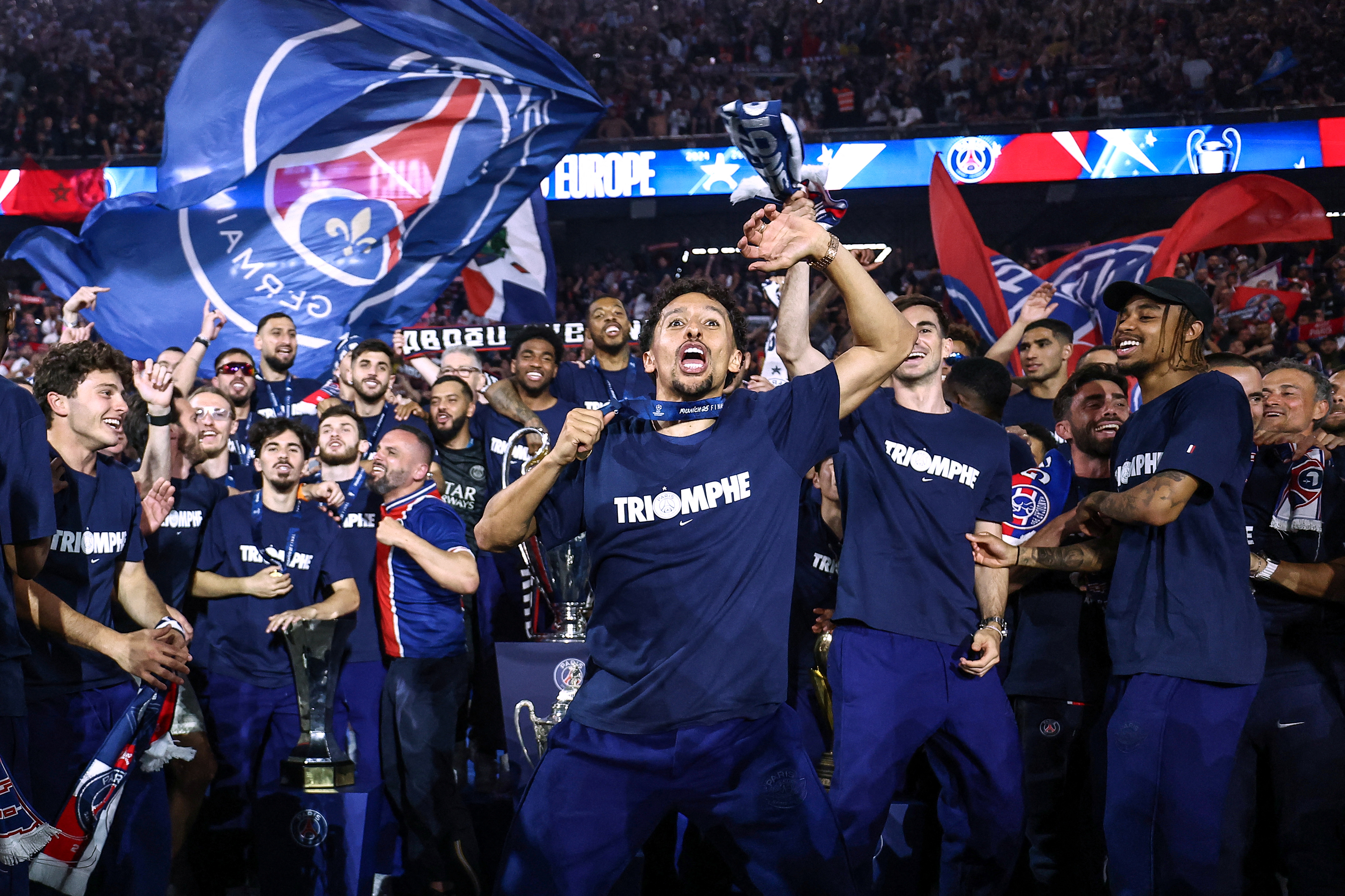 Paris Saint-Germain's Marquinhos celebrates with supporters and teammates during a ceremony to present the trophy a day after the club won the UEFA Champions League