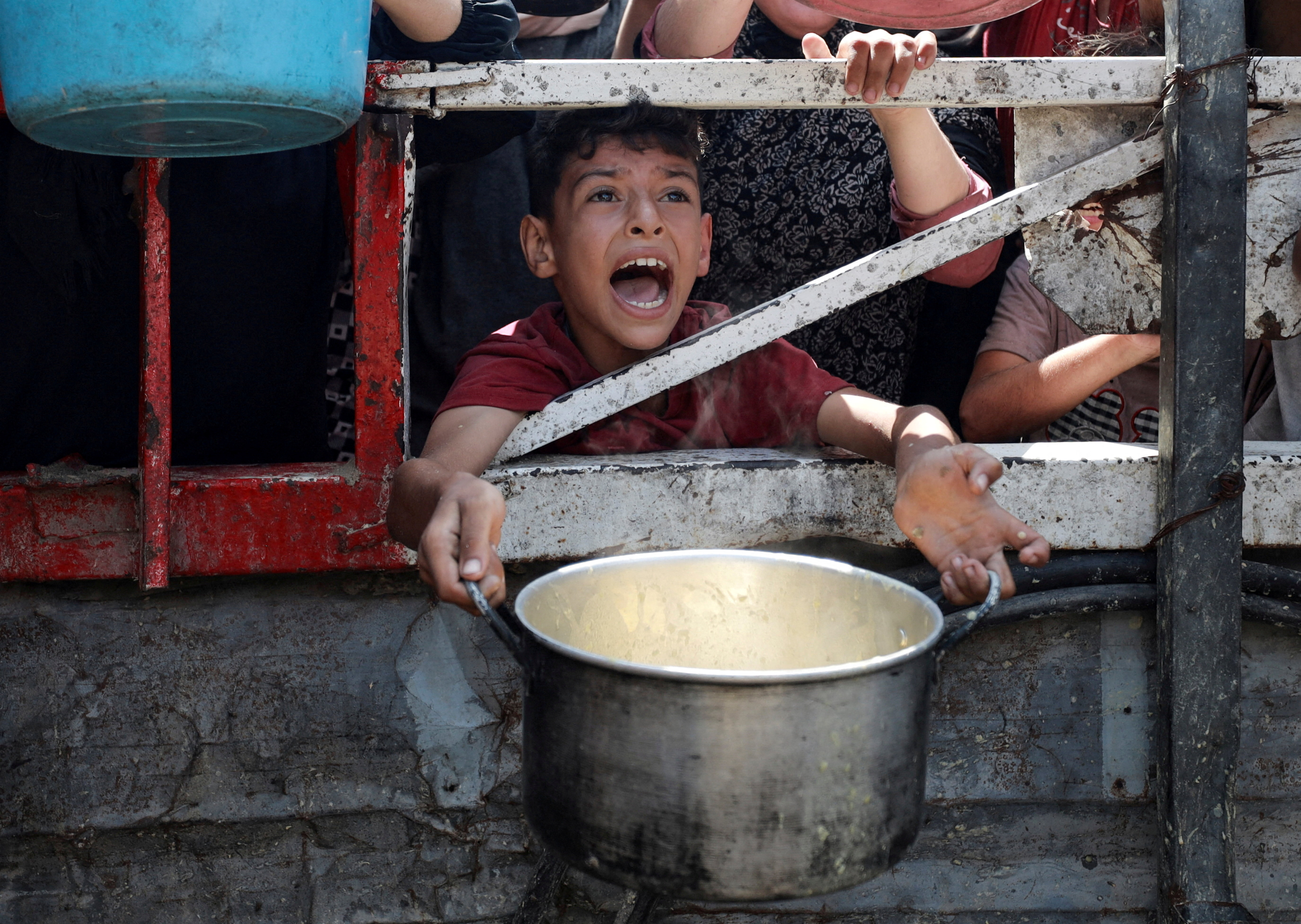 A Palestinian reacts as he waits to receive food from a charity kitchen, amid a hunger crisis