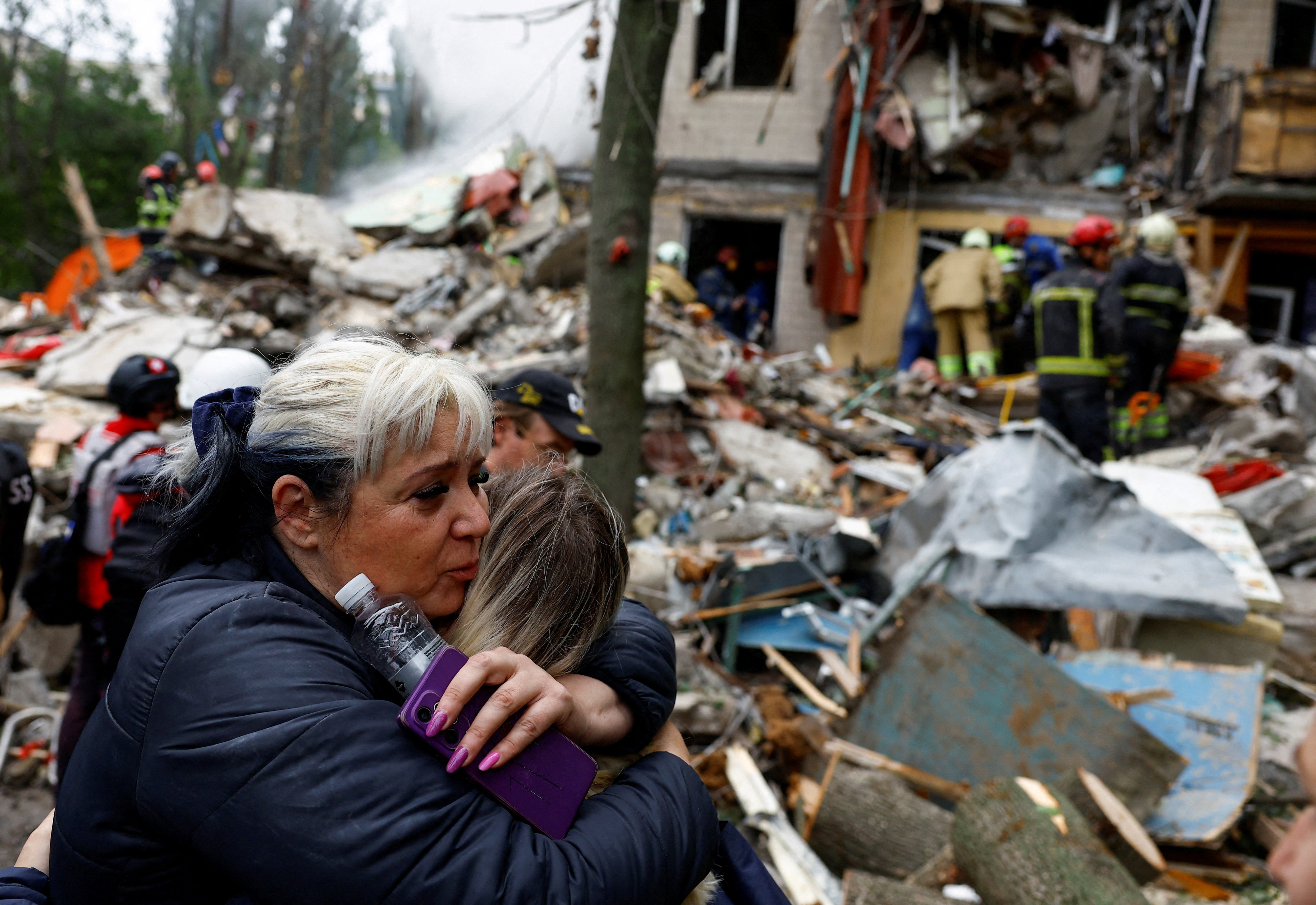 A woman embraces a person at the site of an apartment building hit during an attack.