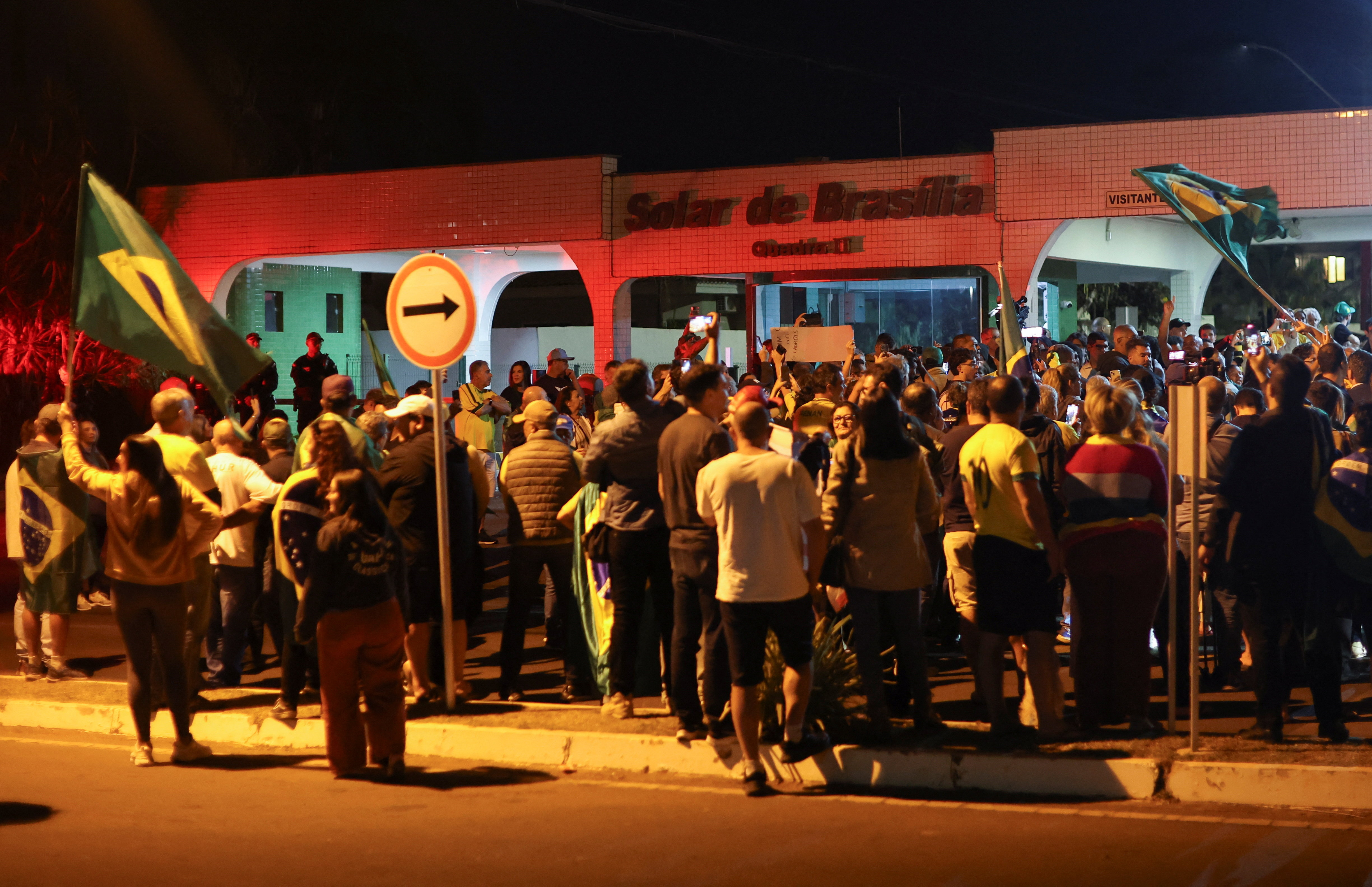 people wave Brazilian flags at a protest at night