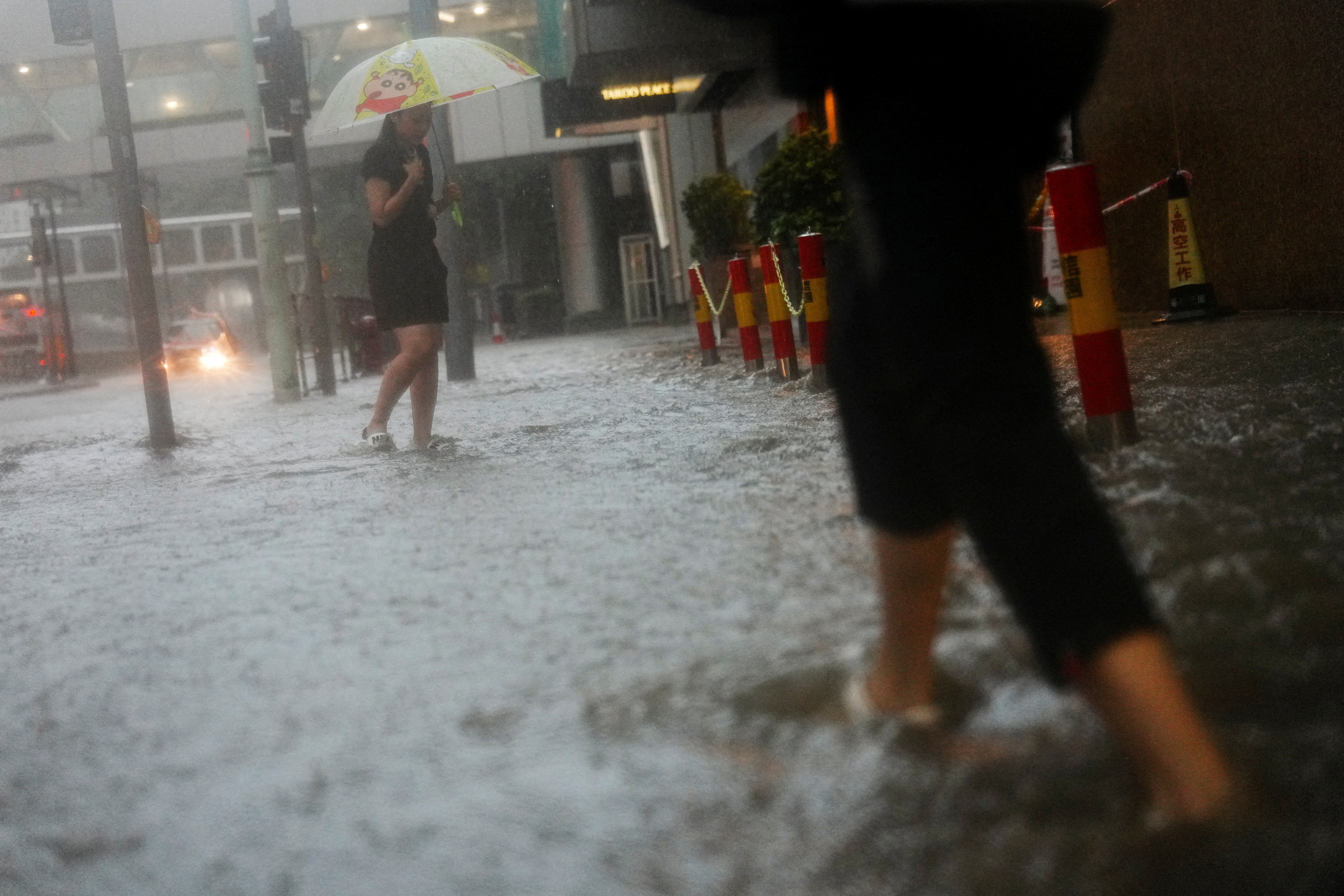 Pedestrian walk past a flooded area during heavy rains, in Hong Kong, China, August 5, 2025. REUTERS/Lam Yik